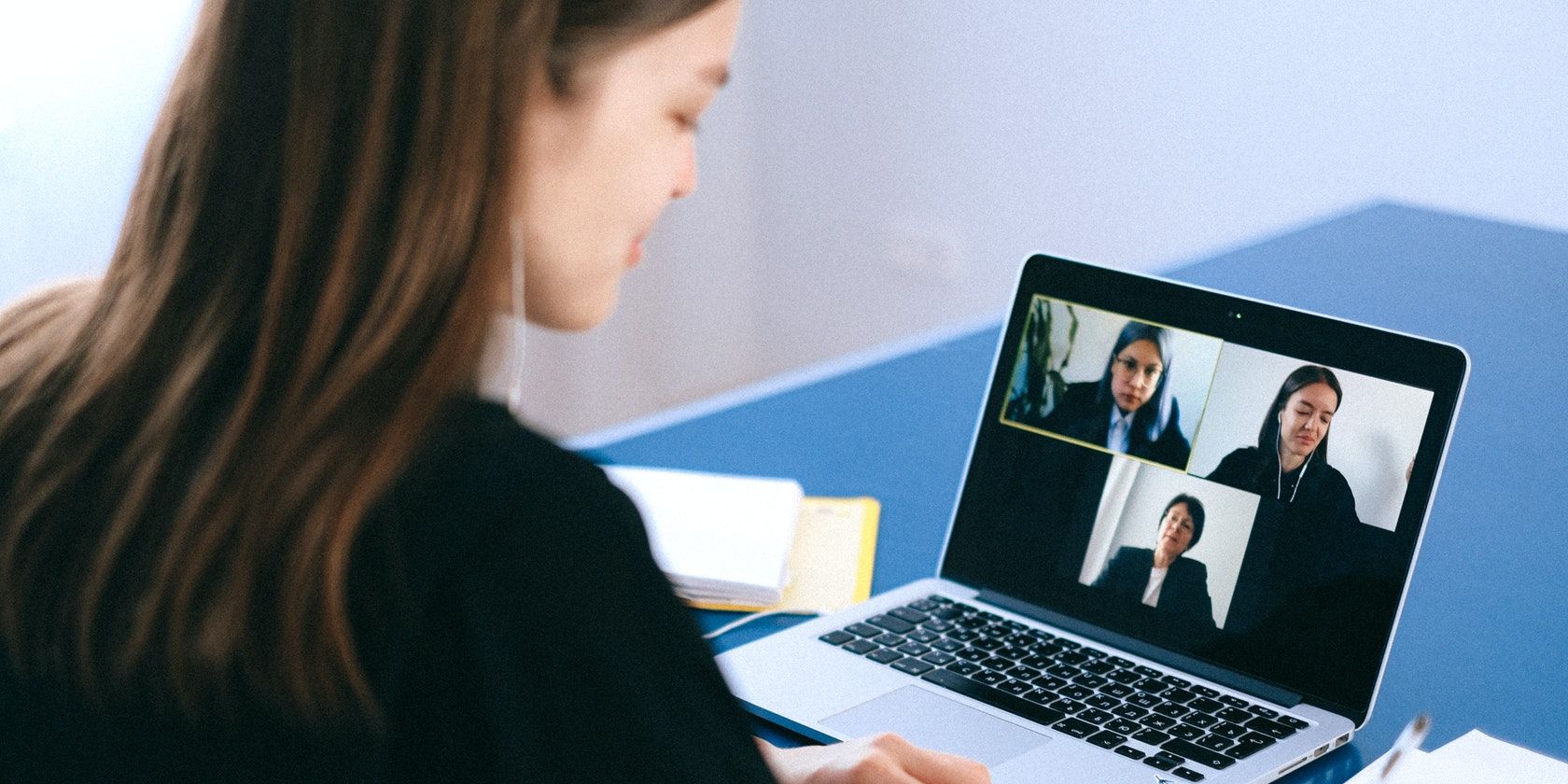 Woman using her laptop and attending an online meeting with three other people