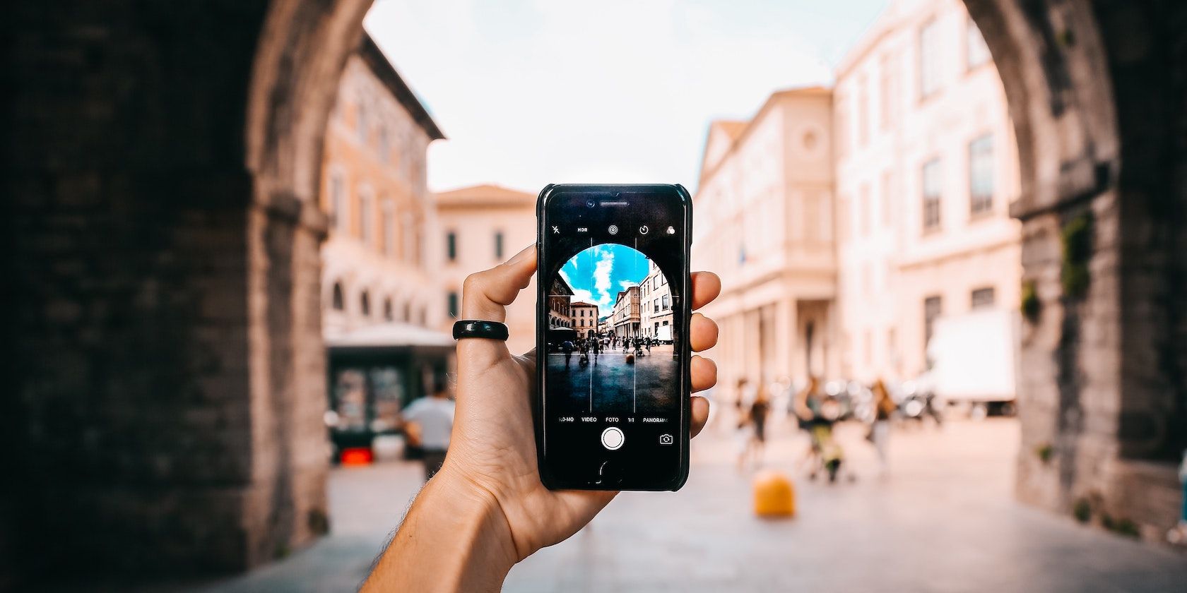 A hand holding a phone that is taking a picture of a street