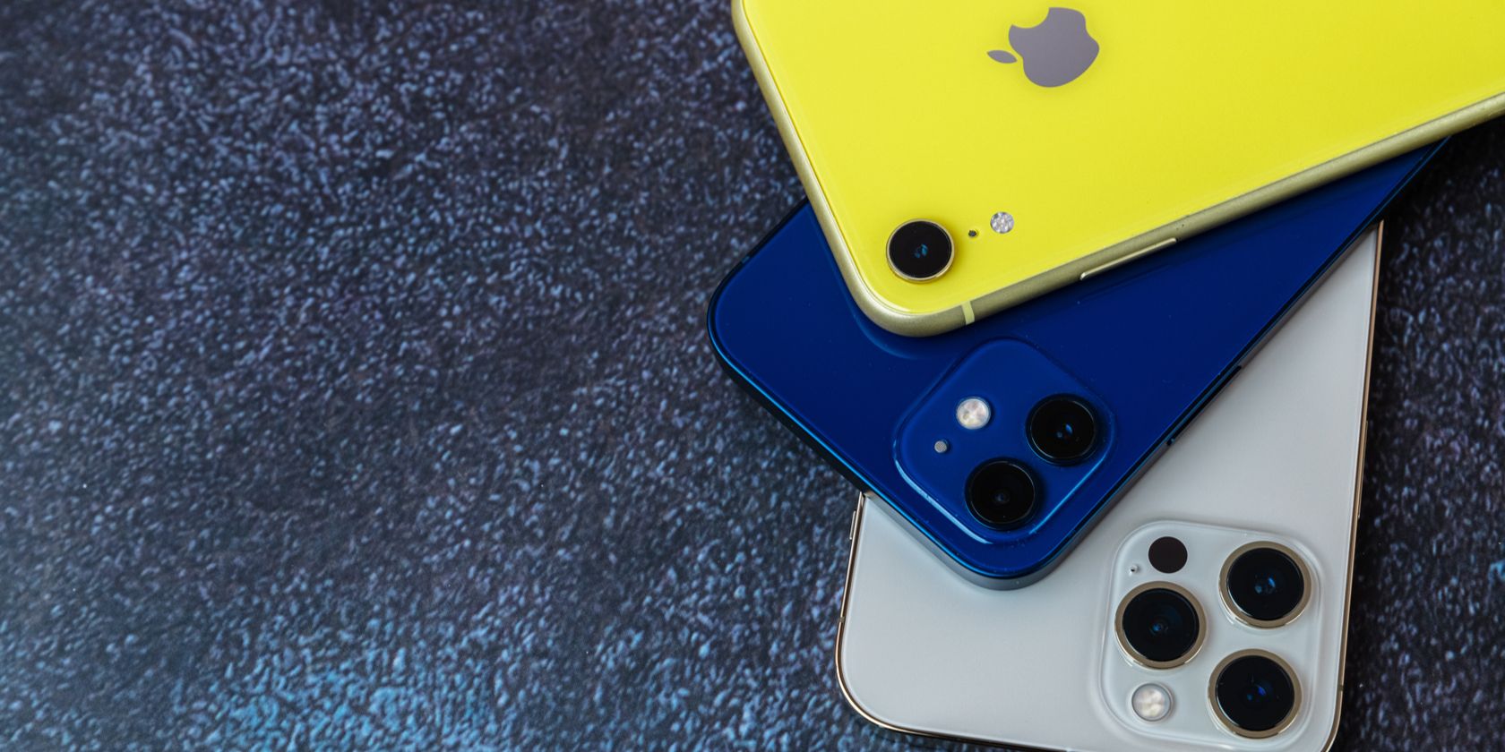 Three colorful iPhone models on a table