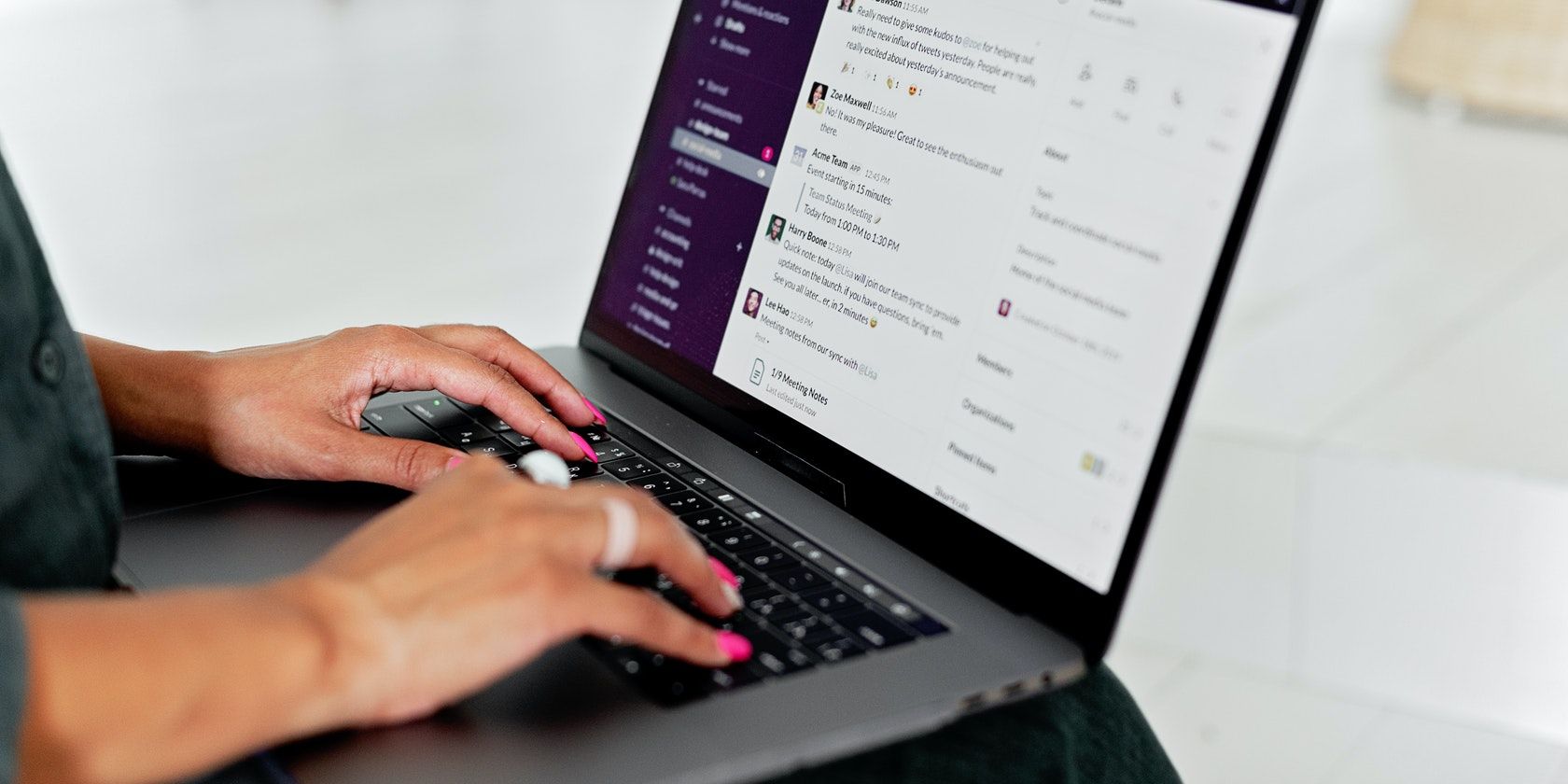 Image shows a woman typing in Slack on a laptop
