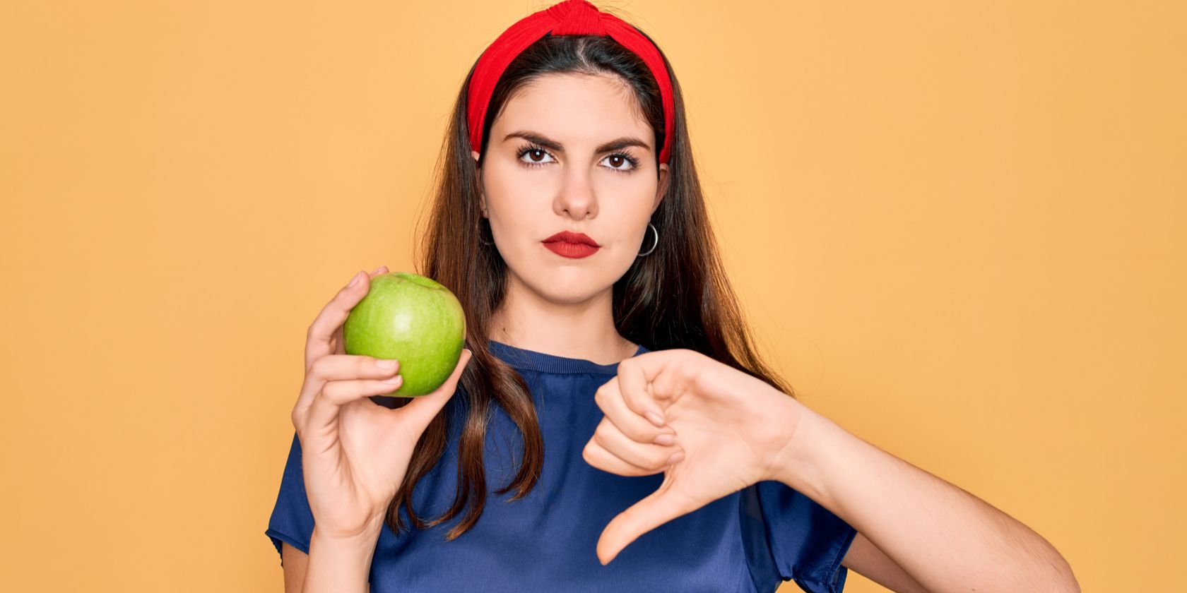 Girl holding apple with thumbs down
