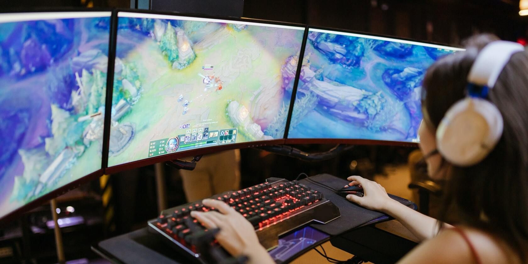 Person gaming on a triple monitor setup.