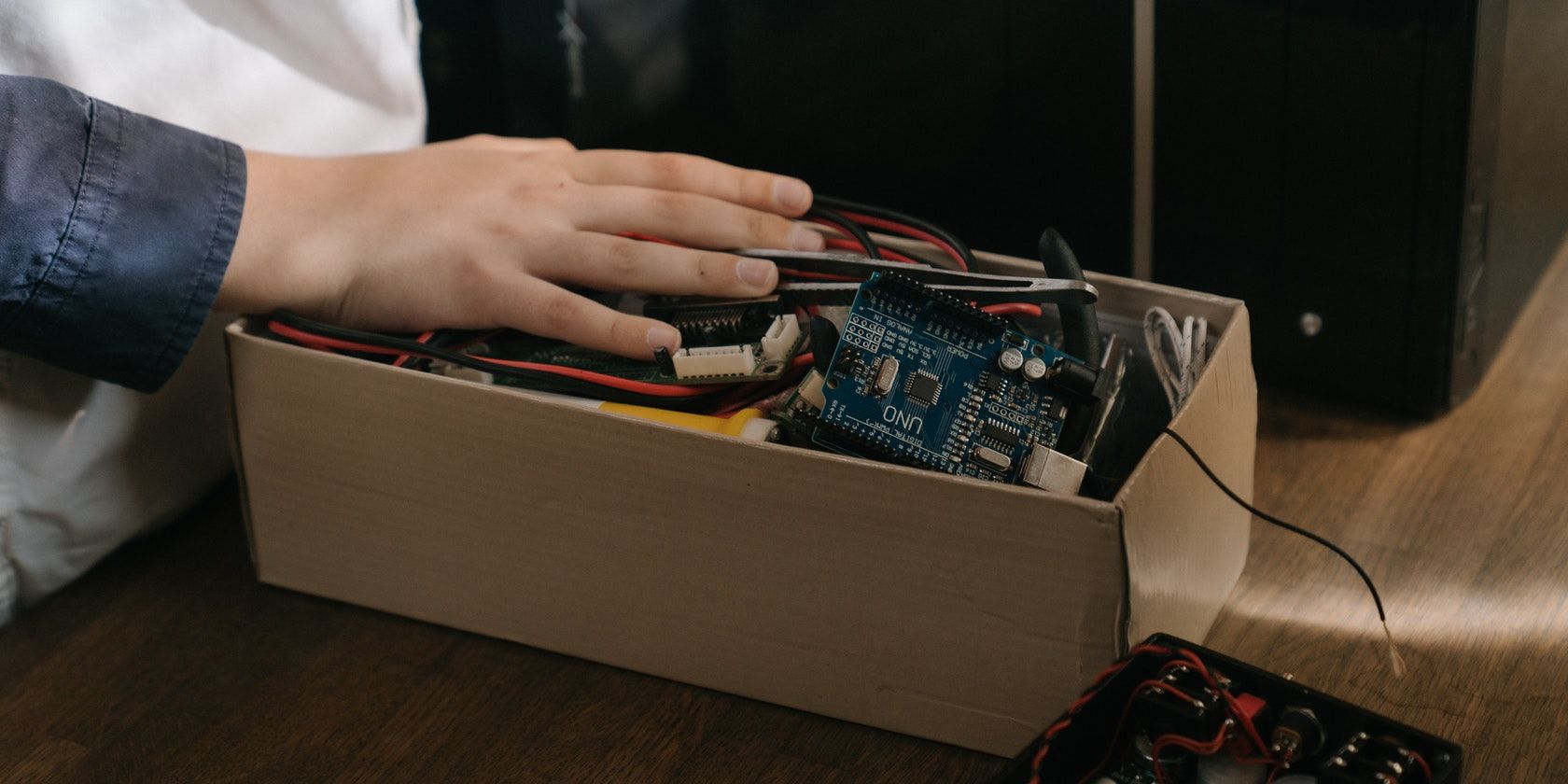 a hand over a box full of electronics and an arduino uno