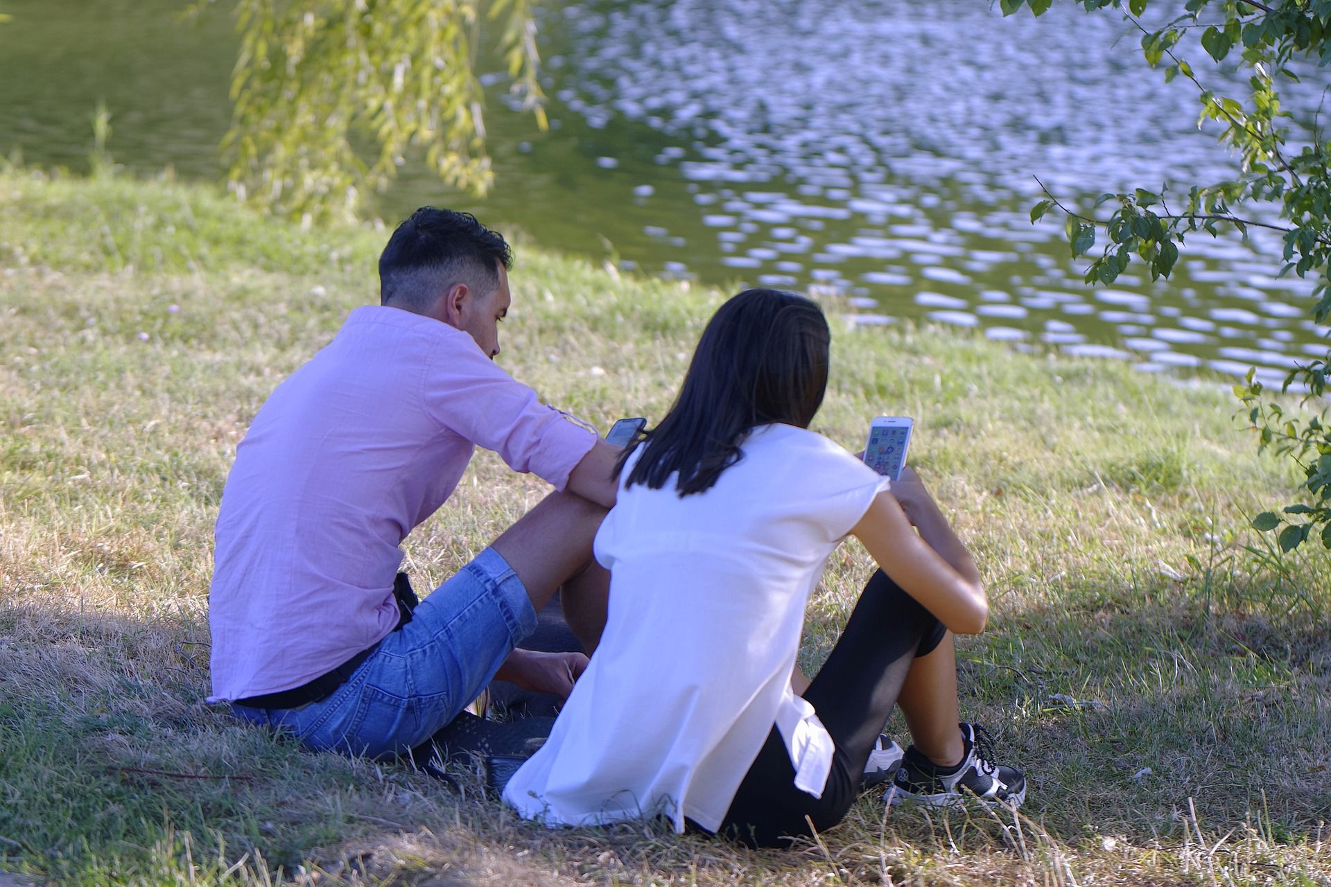 Couple sitting on green grass by lake