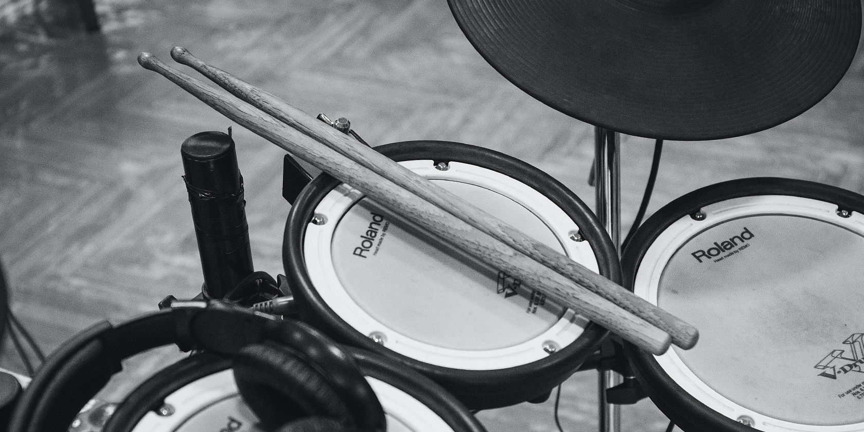 black and white image of an electric drum pad and drumsticks