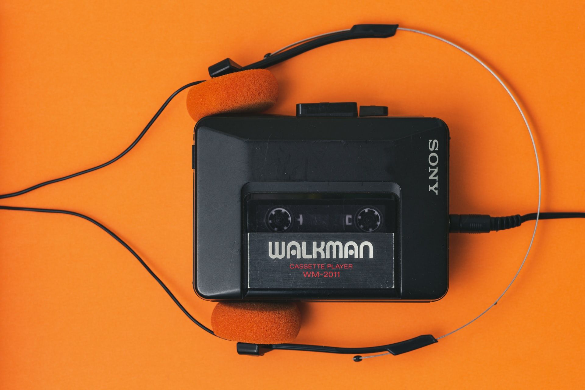 Image shows a vintage Walkman on an orange background