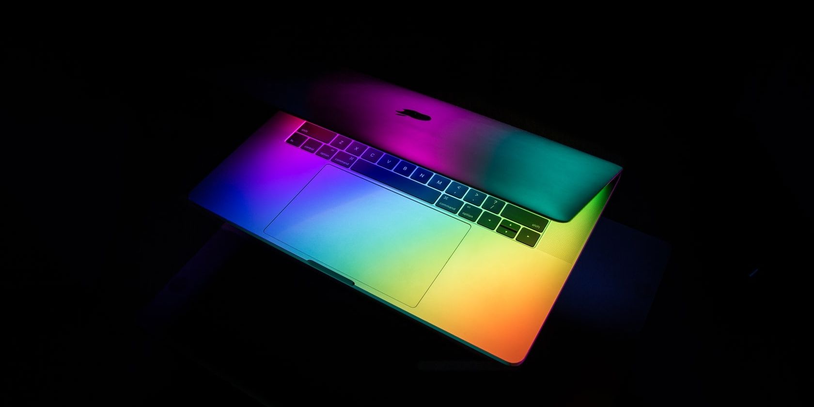 Half open Macbook with raindow-colored lighting.