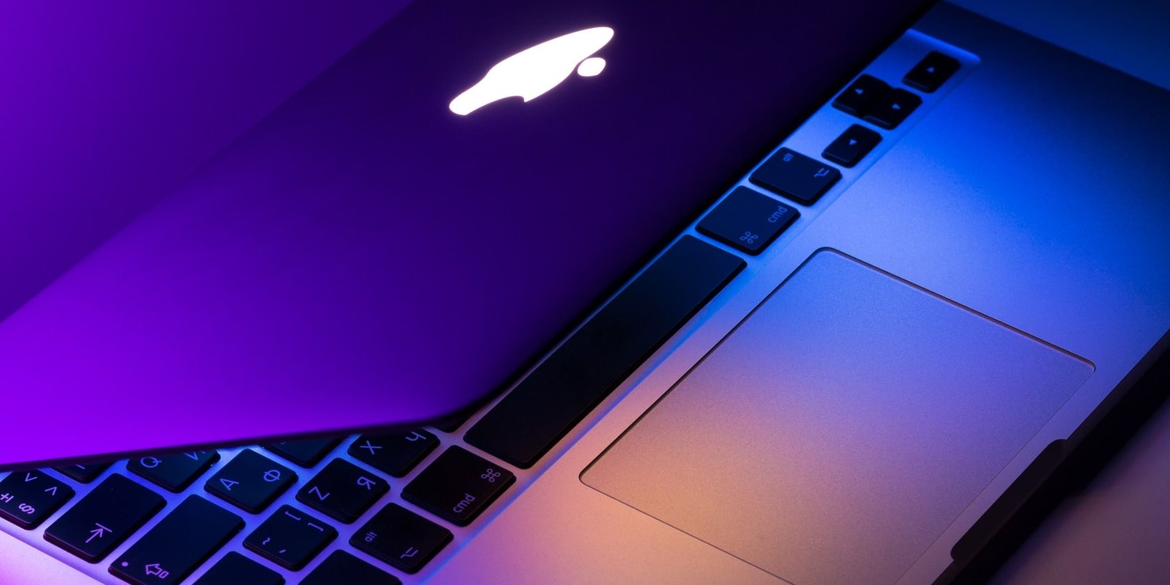 Half open MacBook Pro with purple-blue lighting.