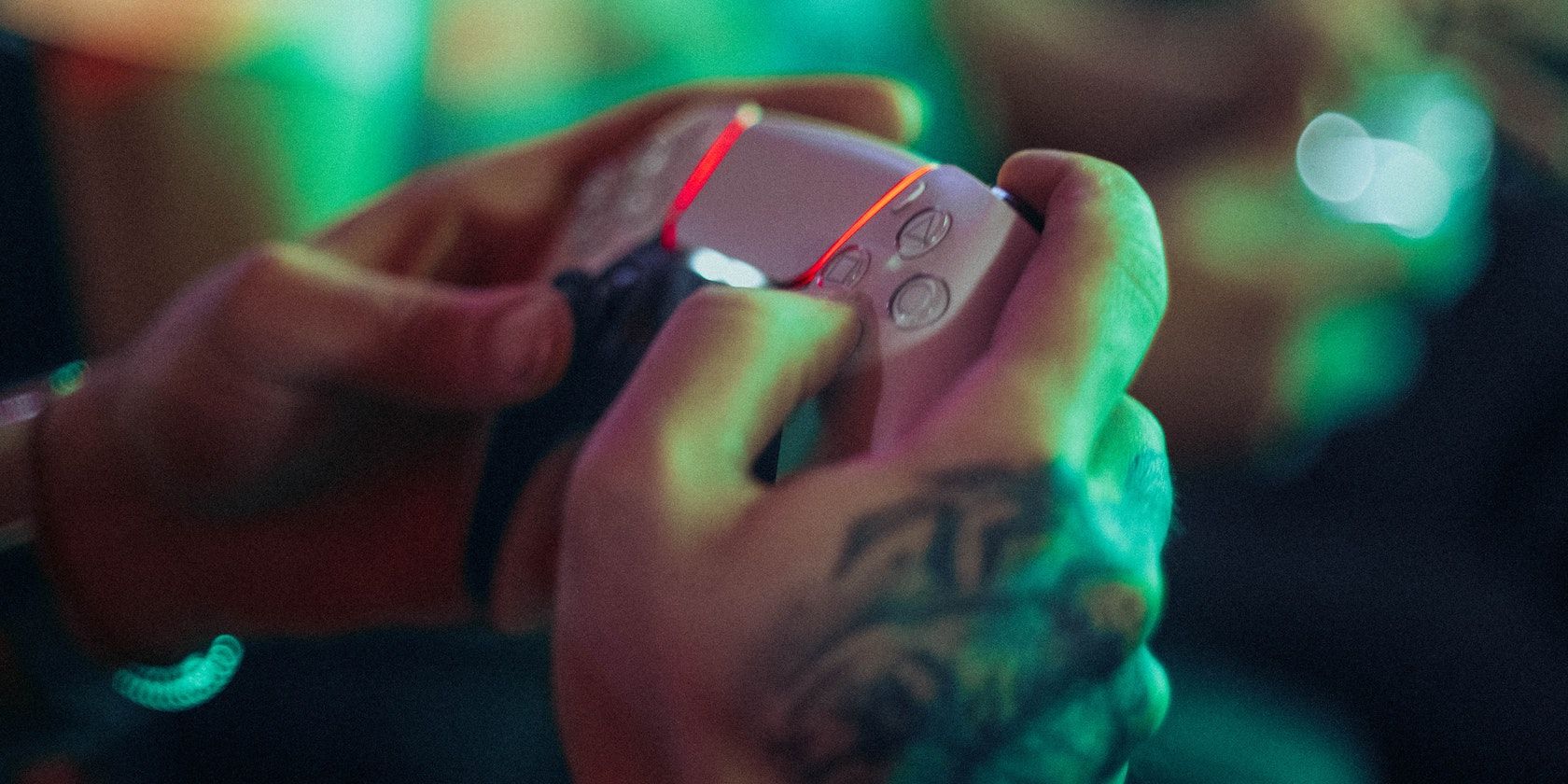 A person using a DualSense controller with tattoos on their right hand