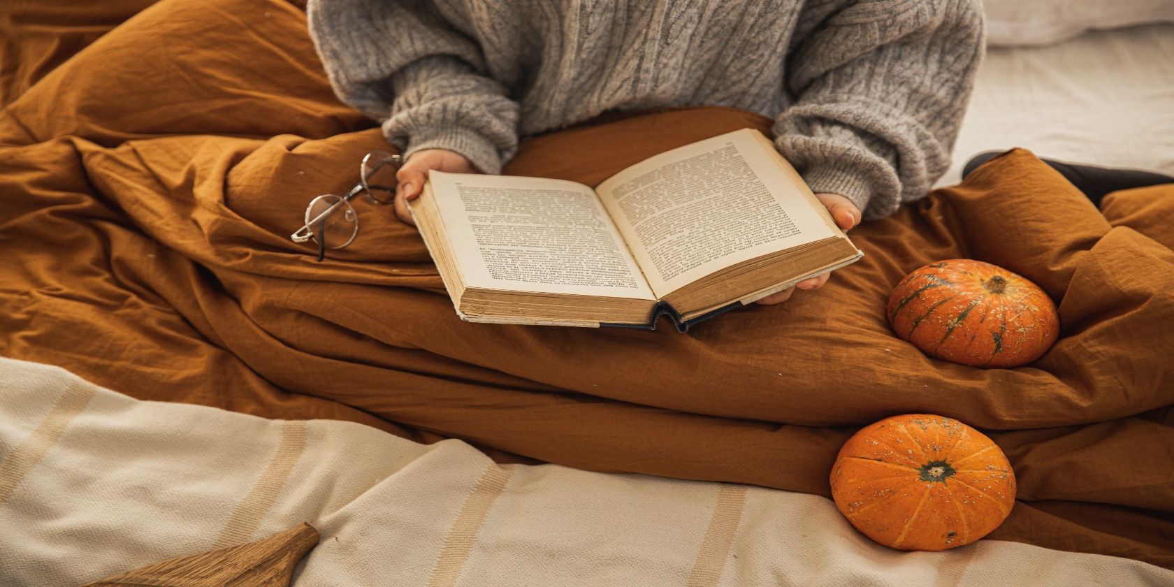 A woman reading a book in blanket with specs in her right hand