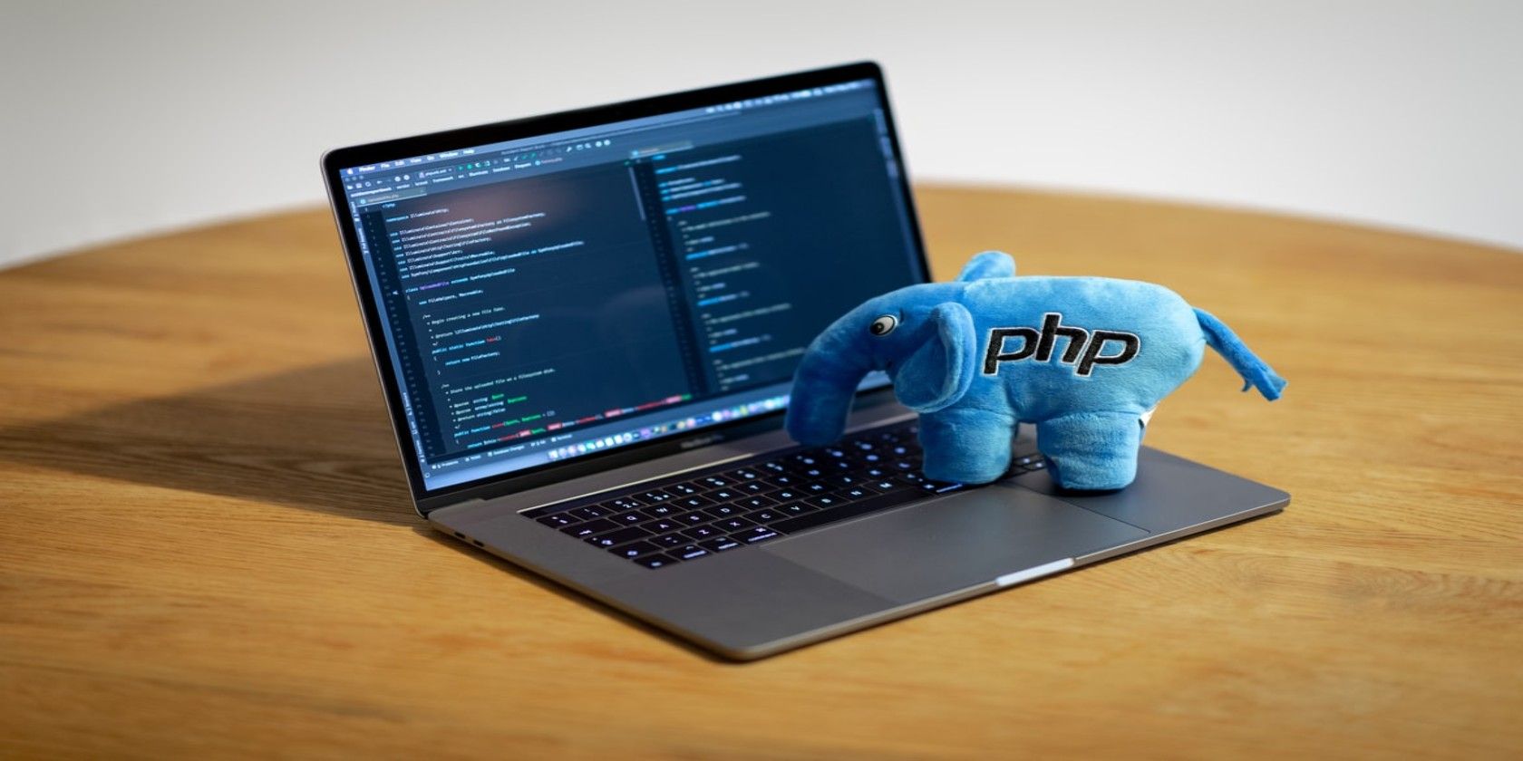 Laptop on desk with an elephant soft toy labelled PHP