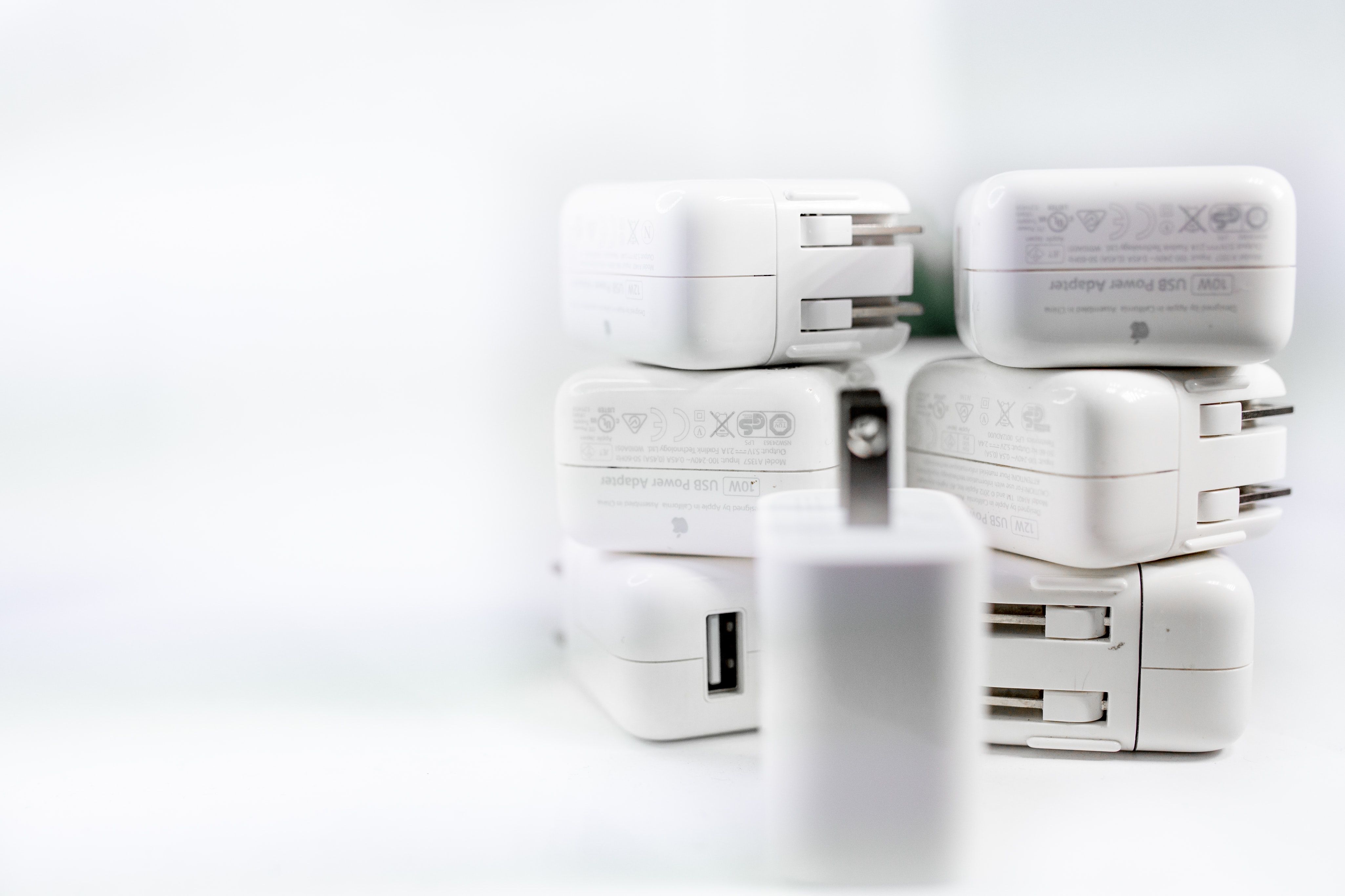 7 iPhone power adapters on a white surface