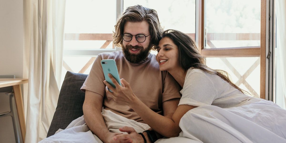 Two people smiling at something on one of their phones
