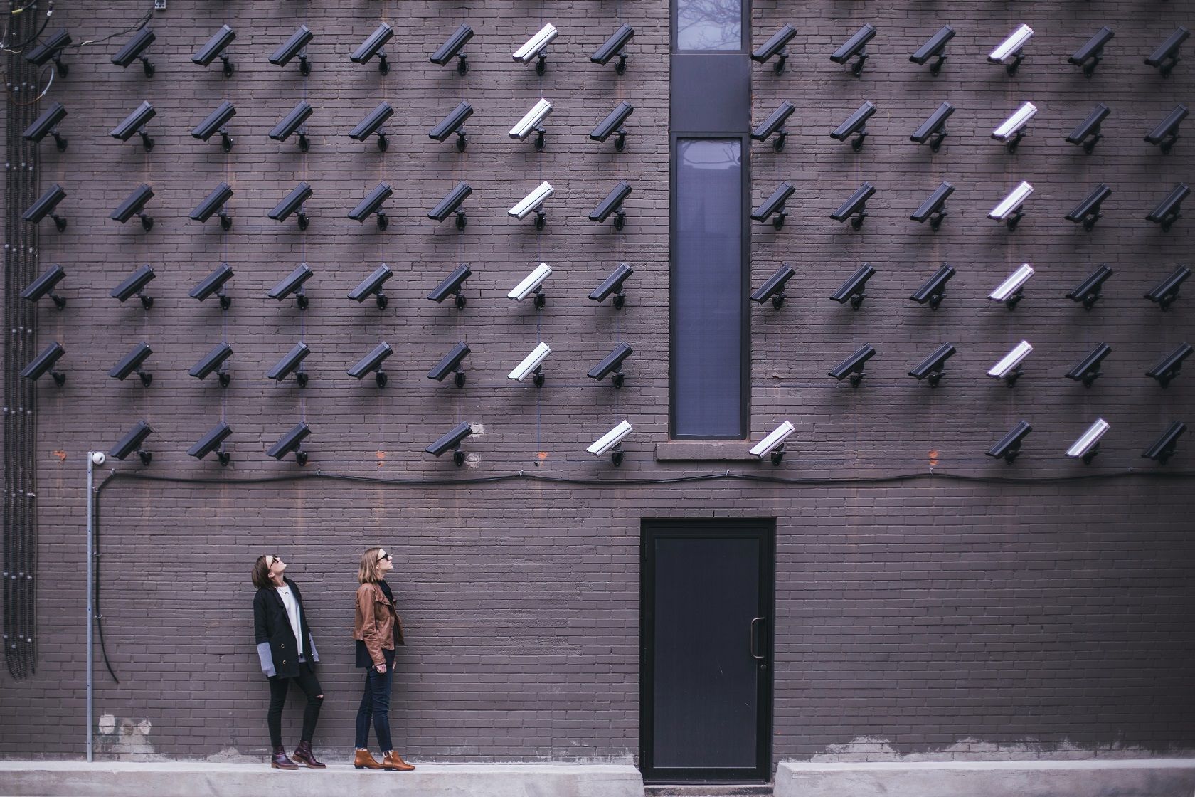 Two women looking up at many security cameras