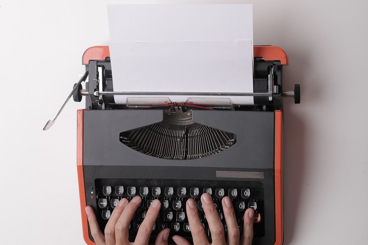 Image shows a woman typing using a typewriter