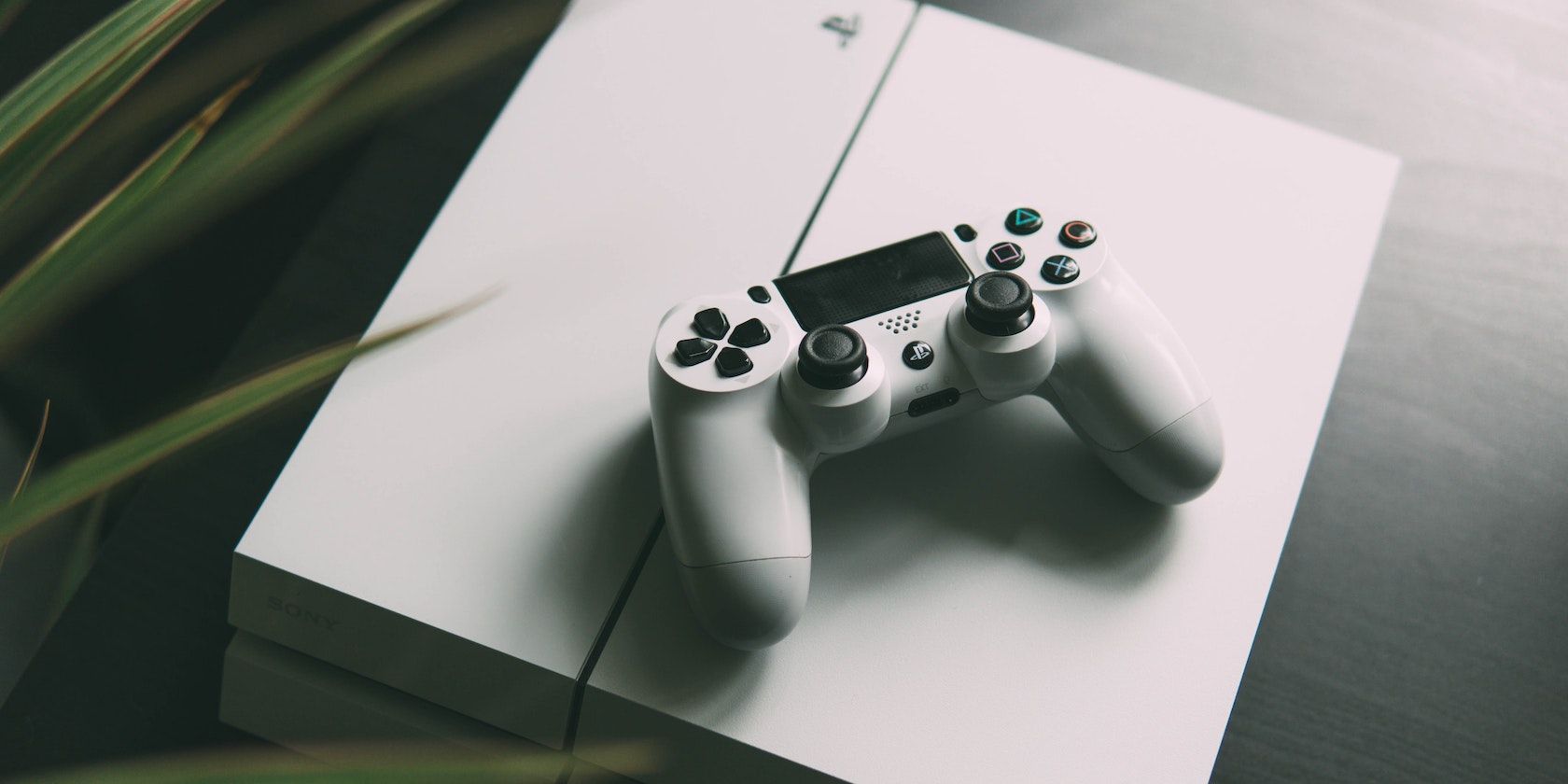 A white PS4 with a white PS4 controller on top of it