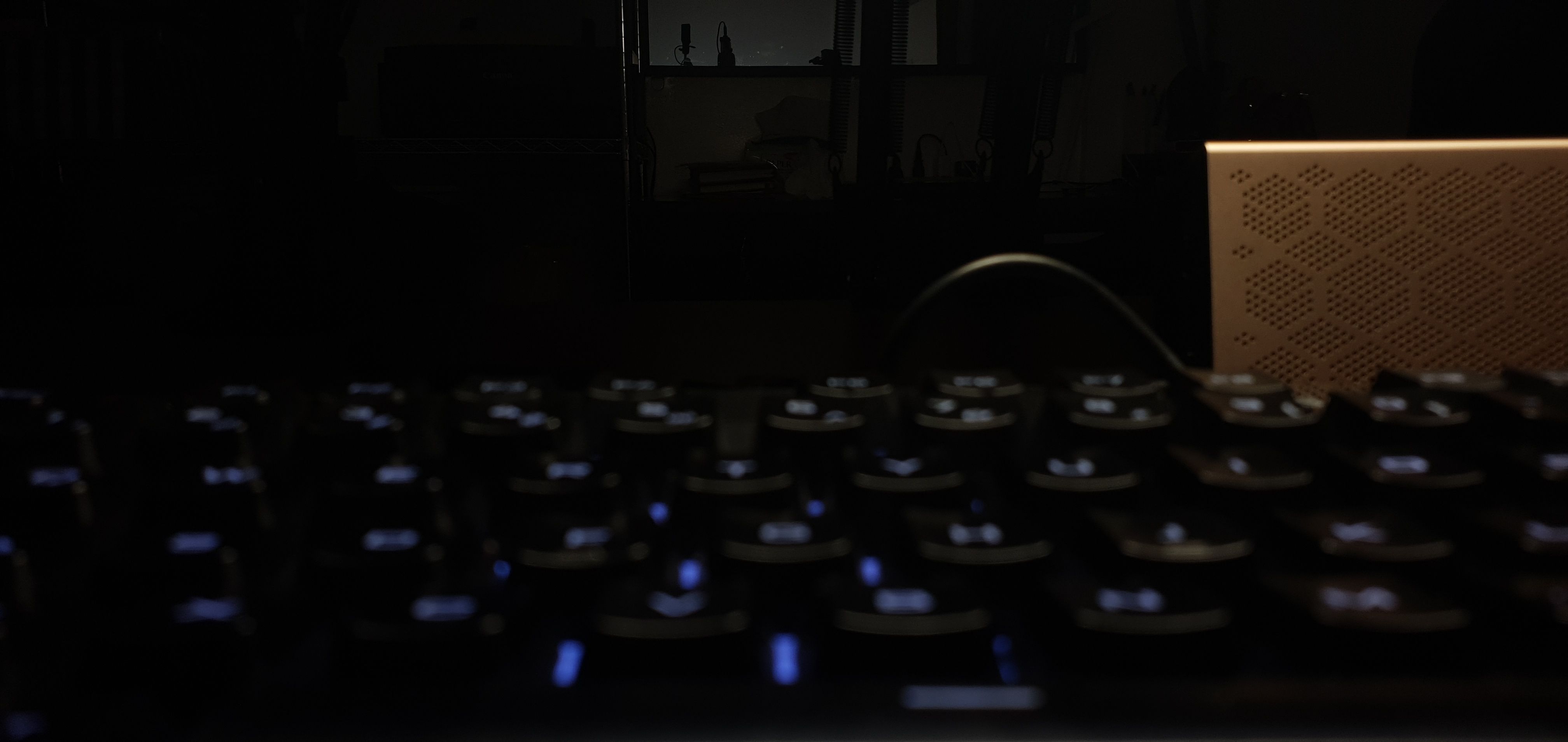 Dark, underexposed image of an office with a keyboard in the foreground