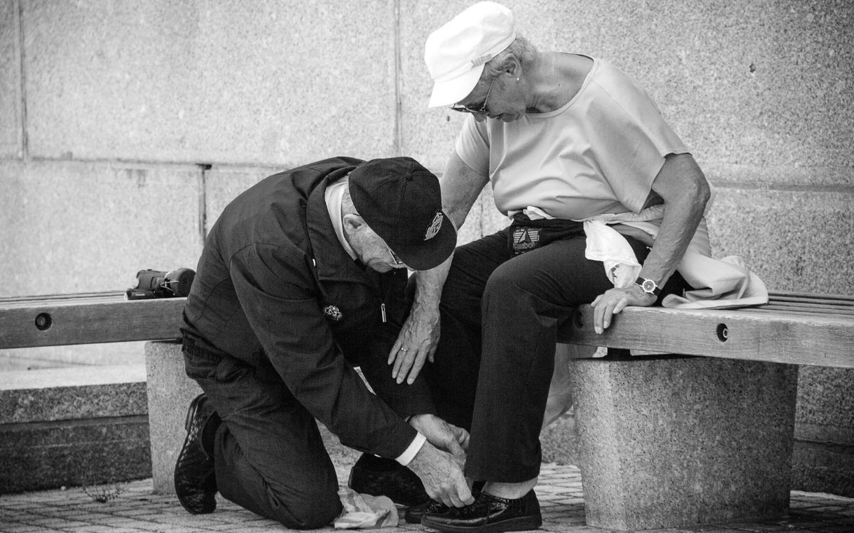 Elder Man helping elder woman to tie her shoes