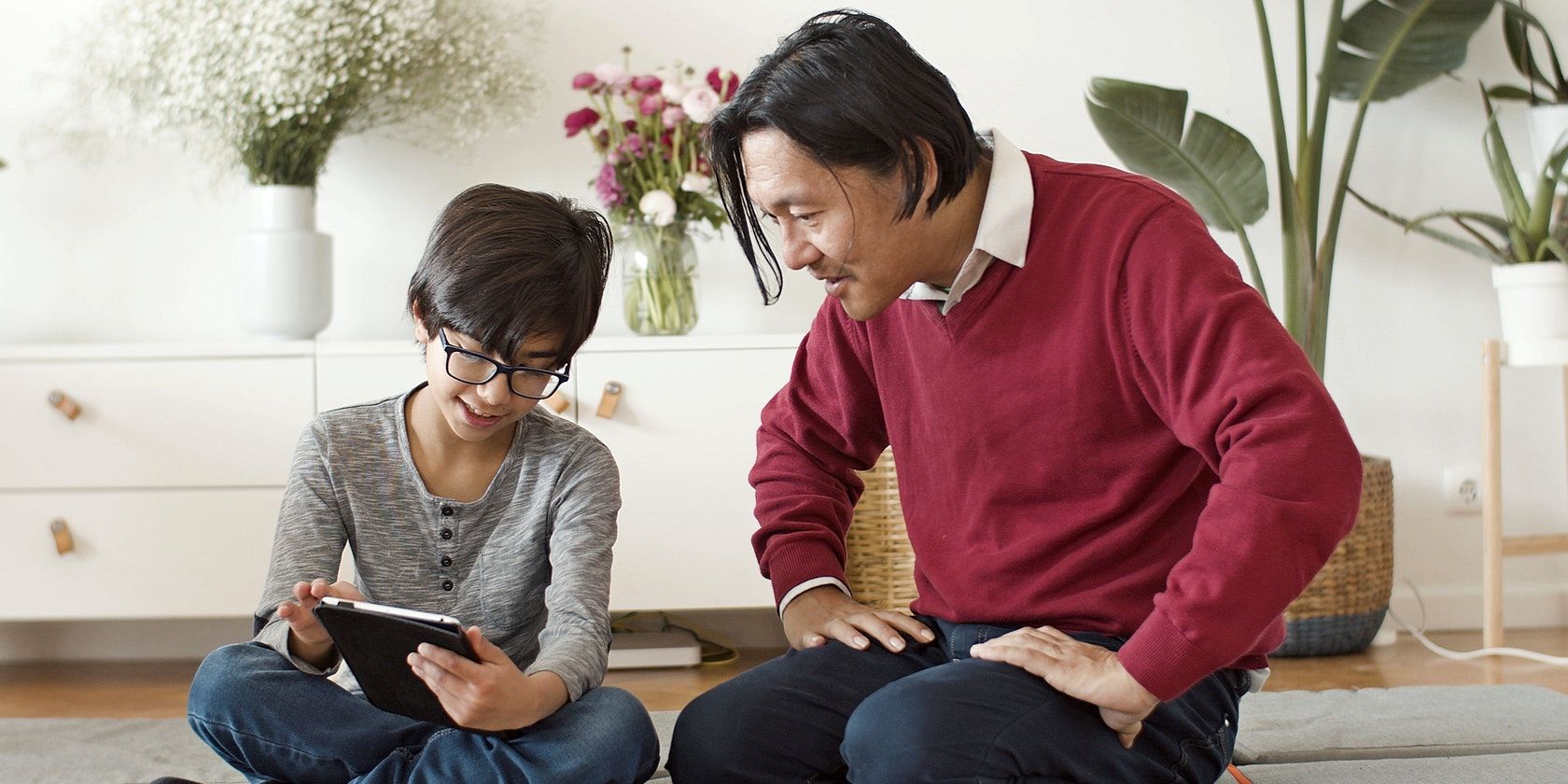 Kid Holding Tablet With Man Sitting Next to Him