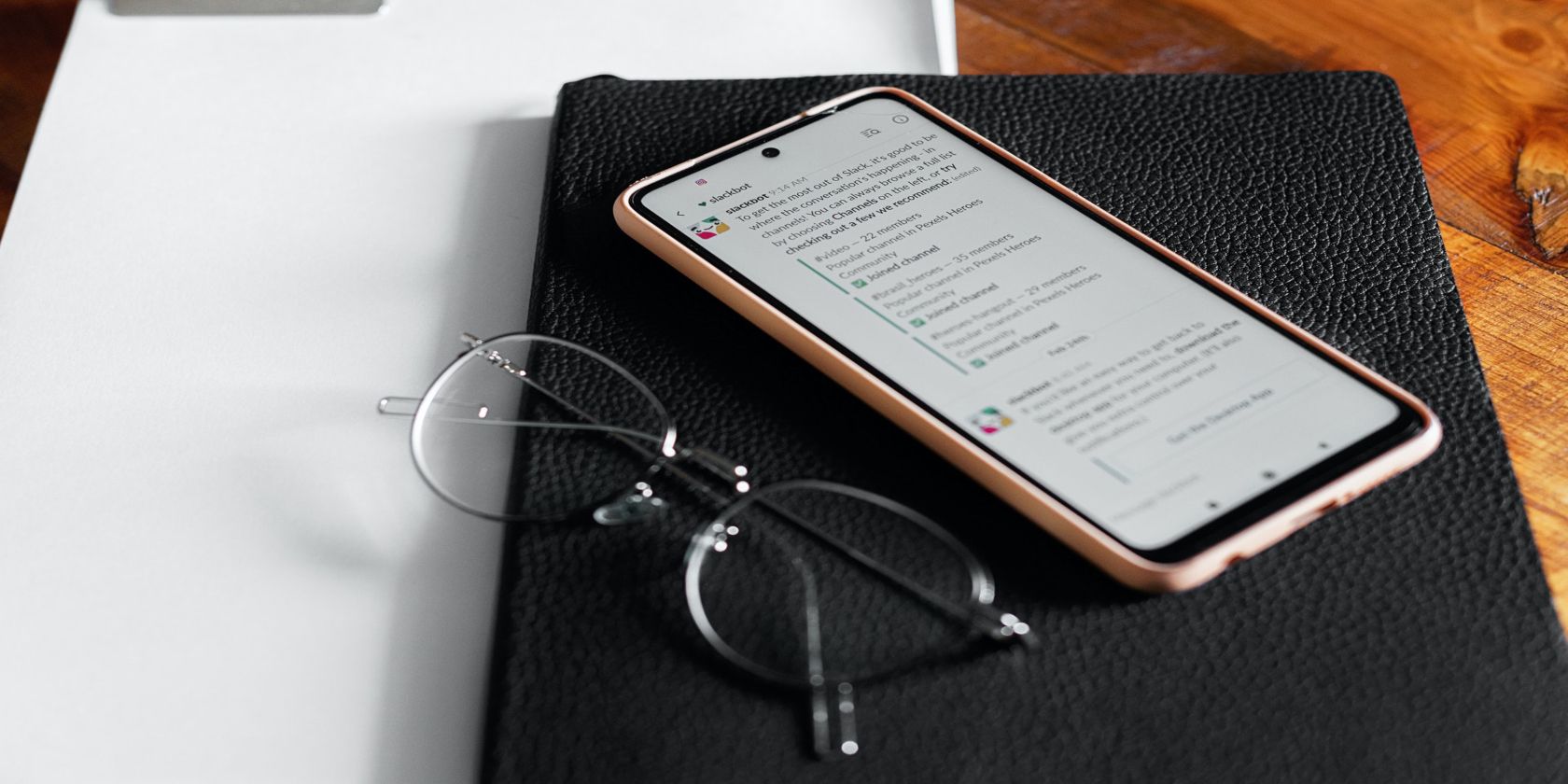 Image shows an iPhone with the Slack app opened on top of a black notebook