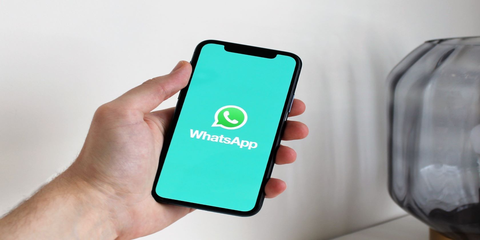person holding a phone showing the WhatsApp app logo