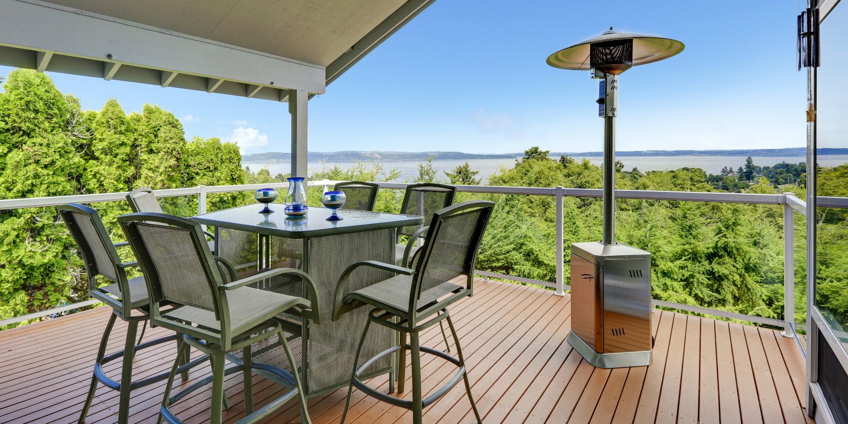Patio area with table, chairs and heater on walkout deck overlooking scenic view
