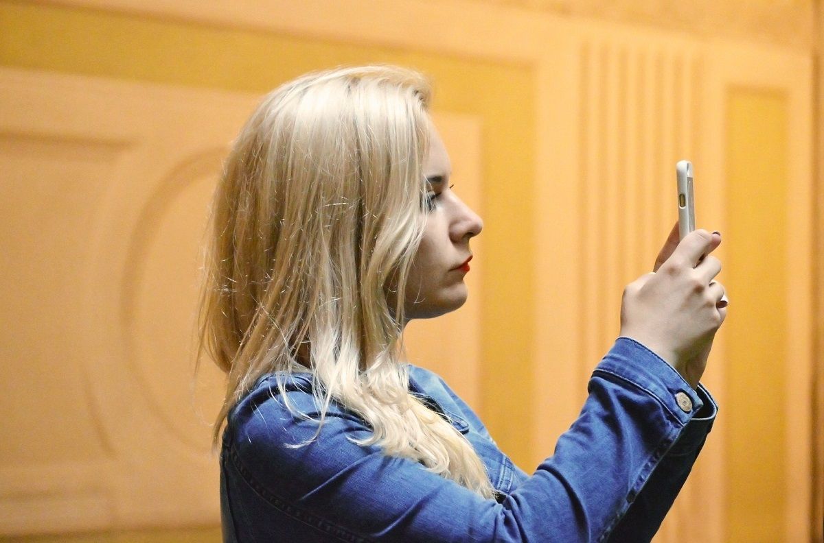 blonde woman taking photo with phone