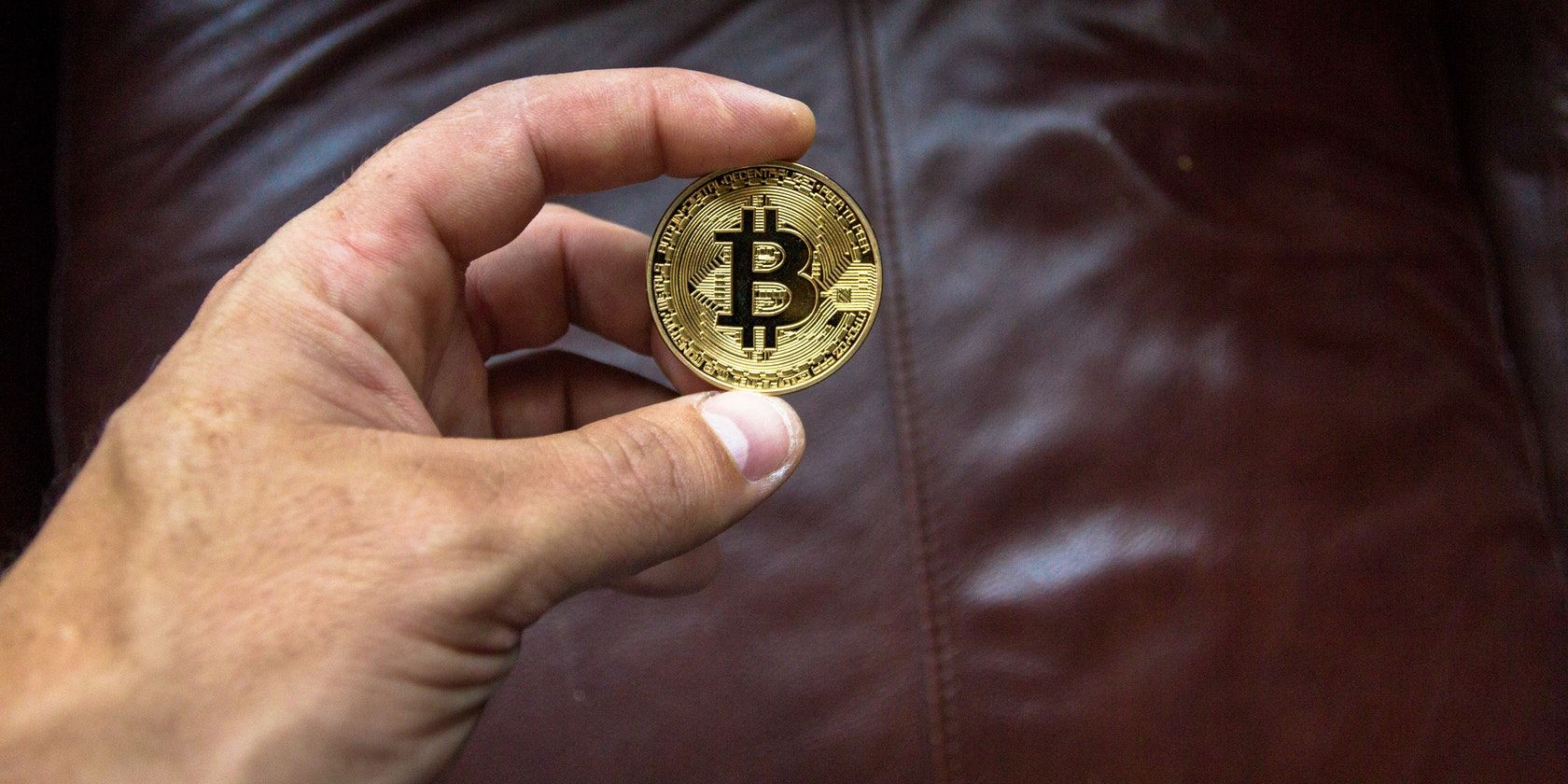 Hand holding a gold coloured Bitcoin