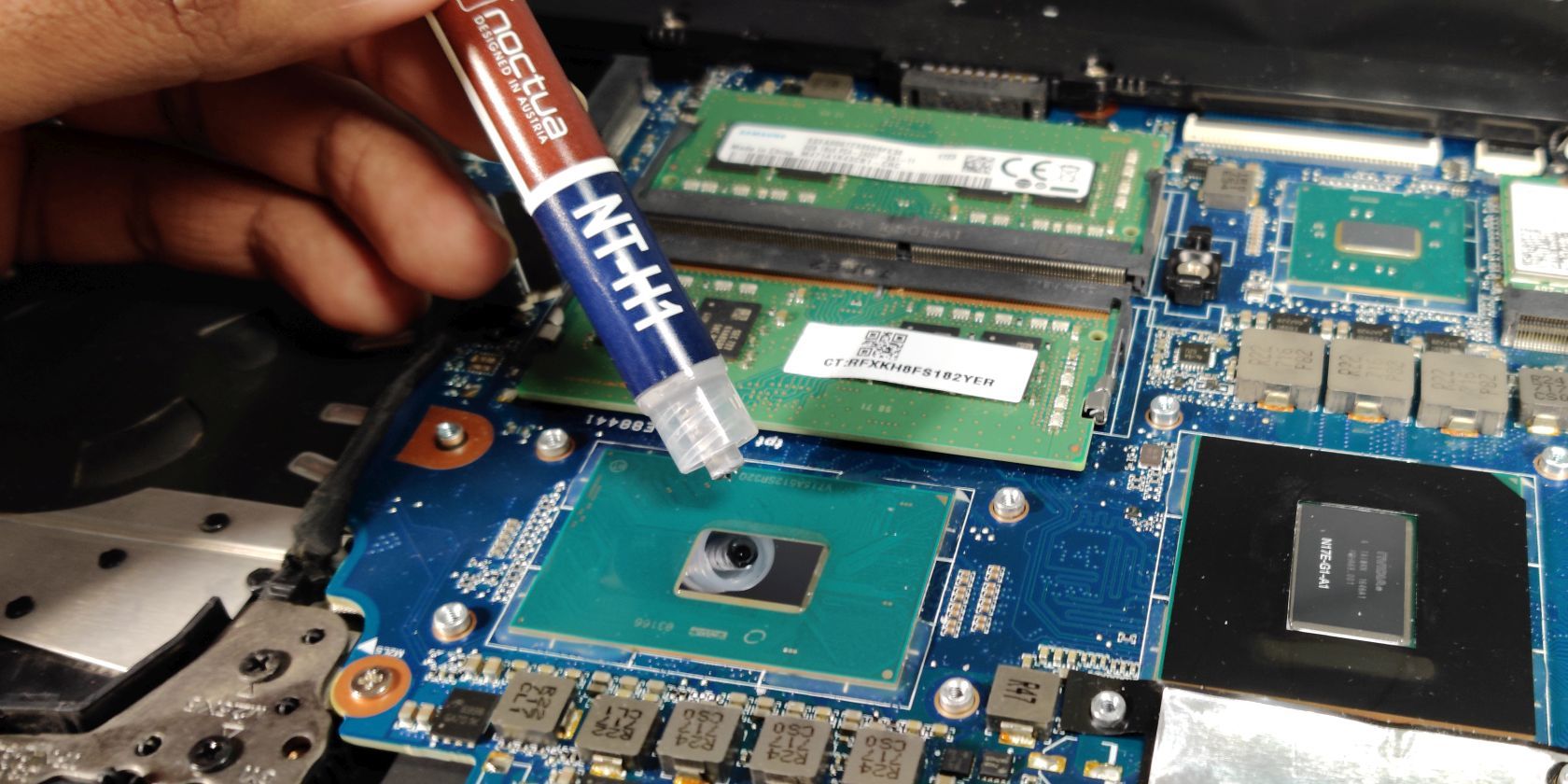 Noctua NT-H1 thermal paste being applied to a laptop CPU.