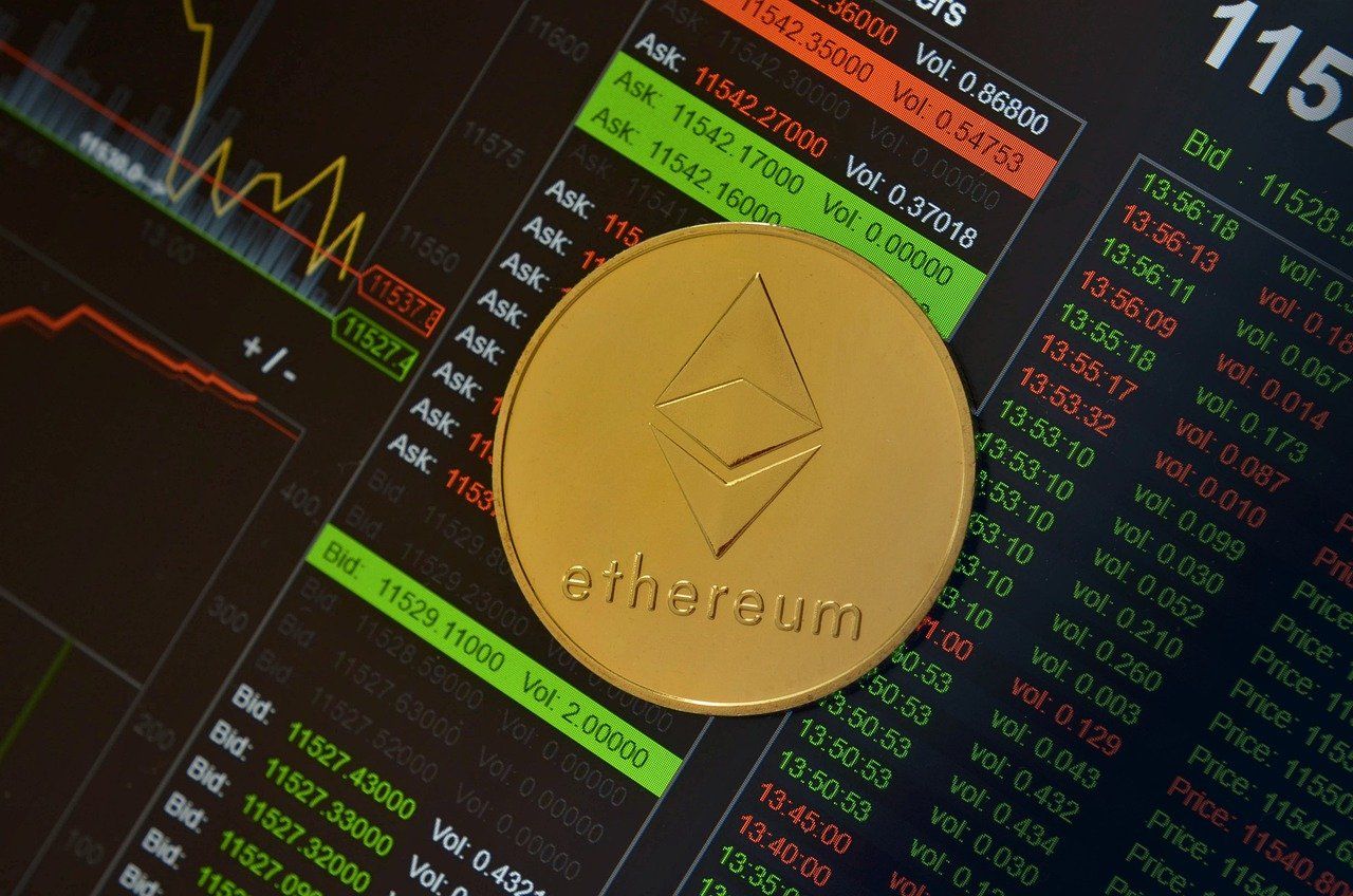 ethereum coin resting on top of a screen that shows stock prices