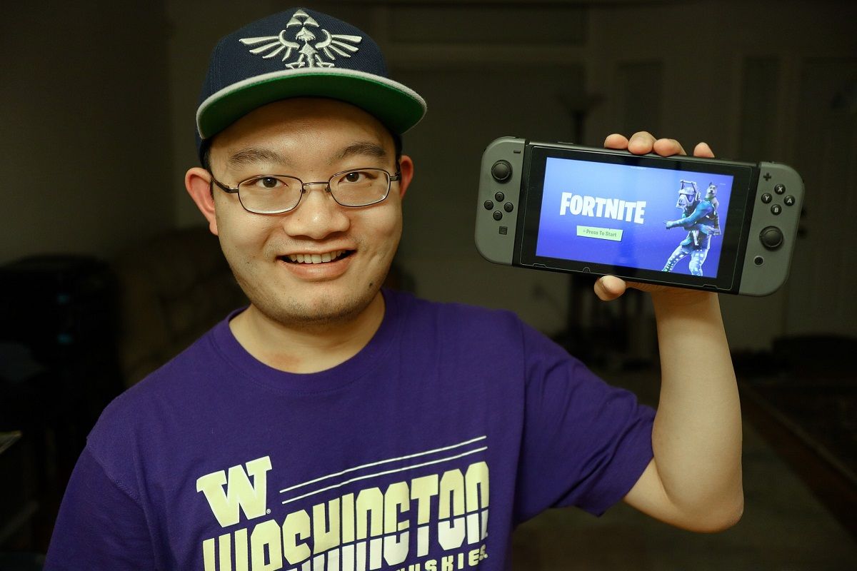 gamer holding phone with Fortnite logo