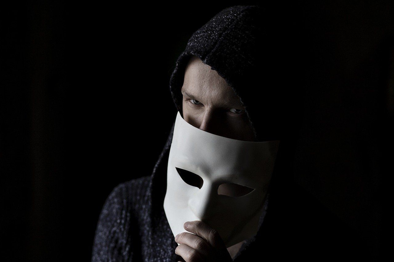 Hacker with face half covered by a mask