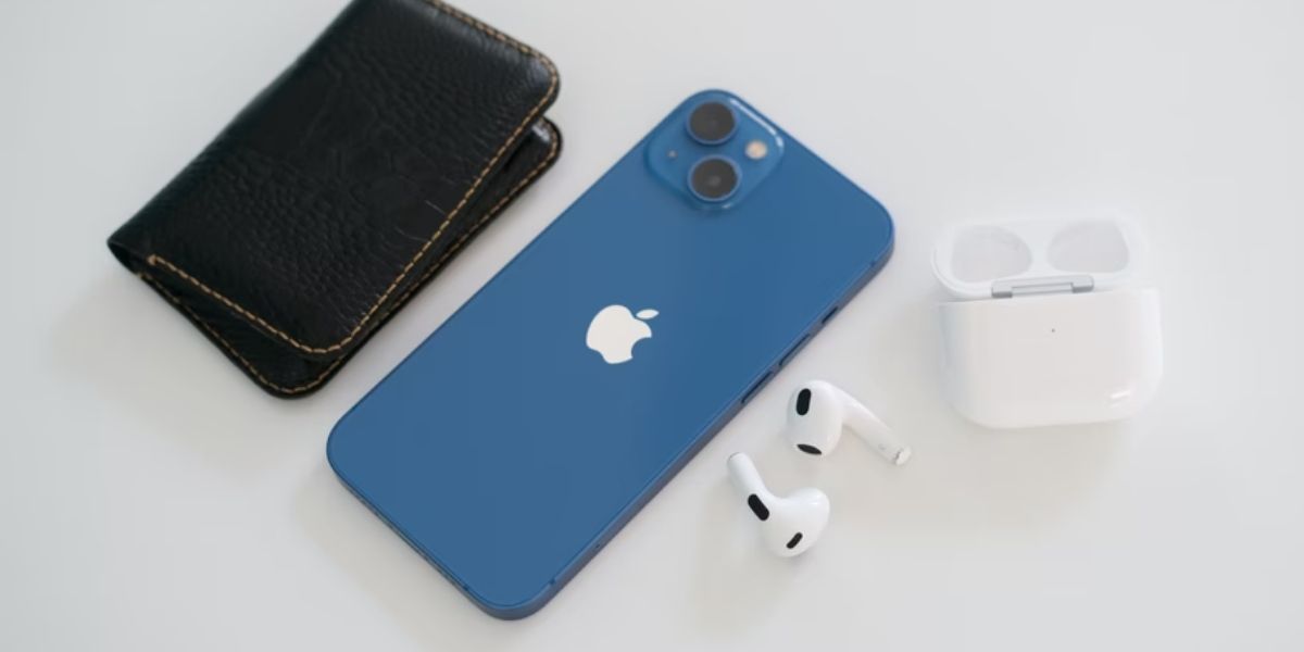 blue iphone 13 on white surface with black wallet and airpods 3