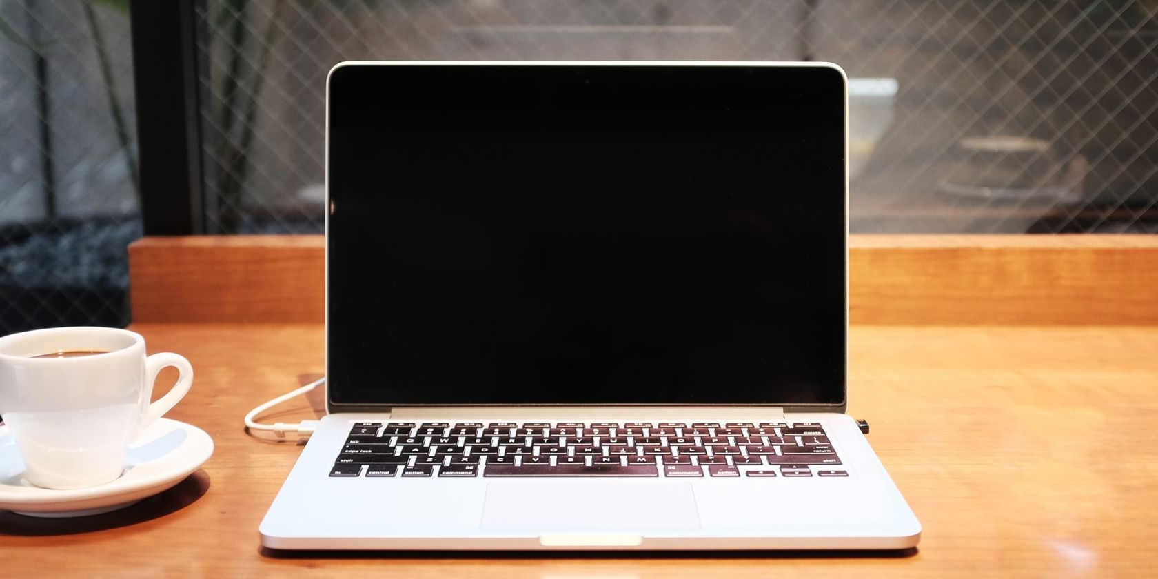Macbook sitting on desk with a coffee mug.