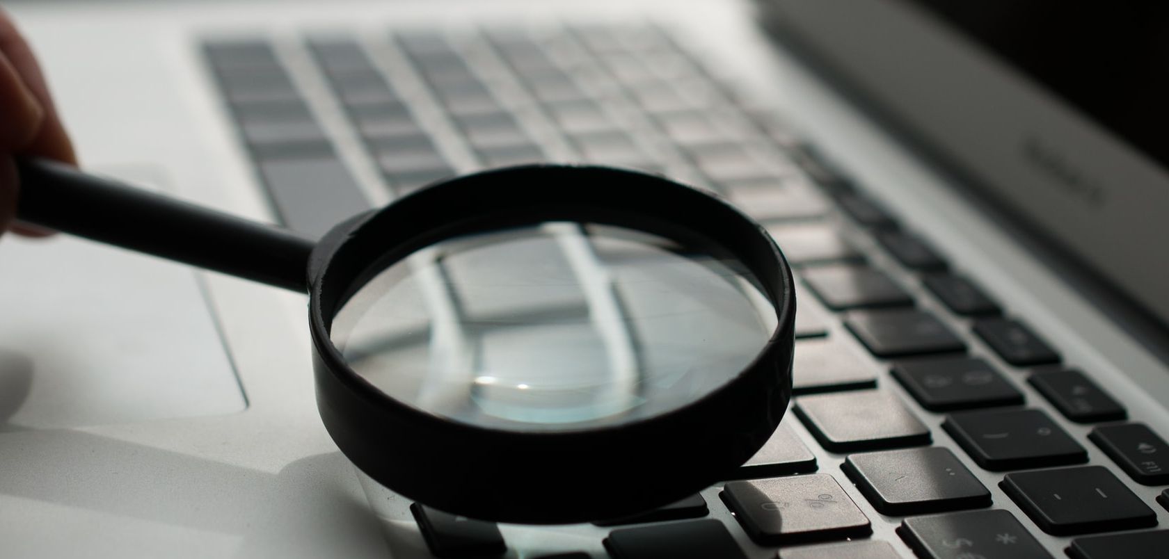 Magnifying glass looking at a MacBook keyboard.