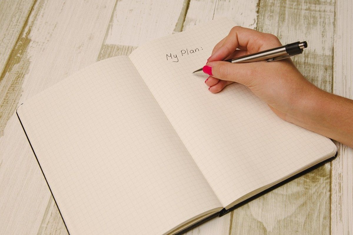 Photograph of Person Writing in Notebook, Page Titled "My Plan". 