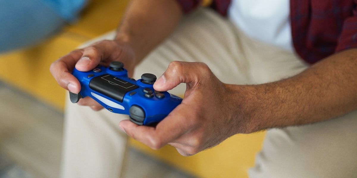 A person gaming with a blue PS4 controller