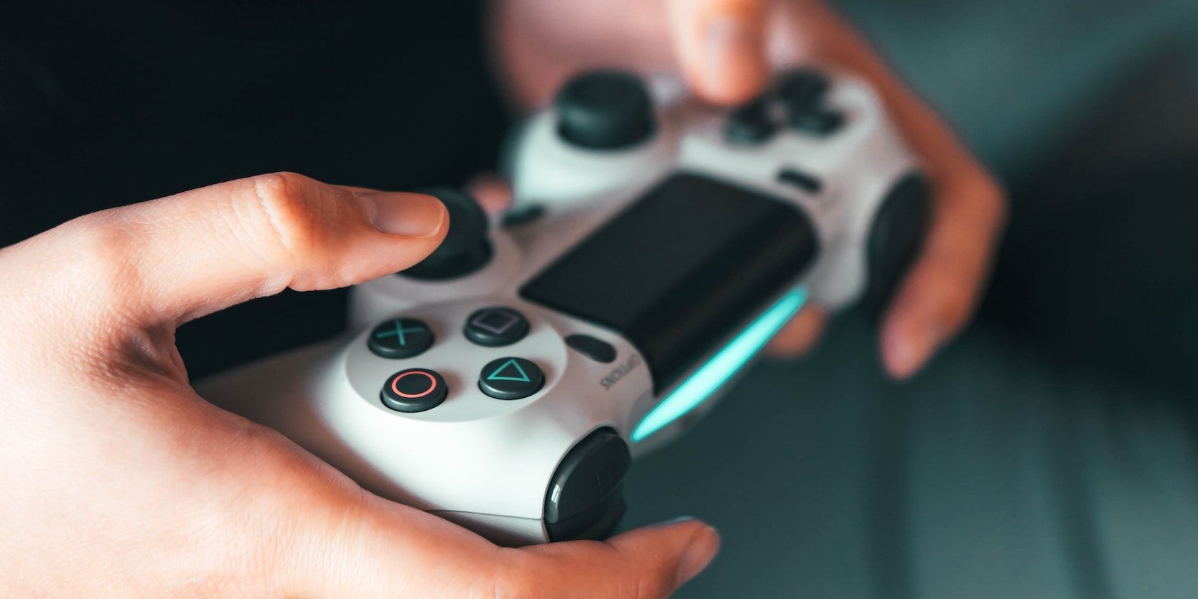 a person gaming with a white PS4 controller