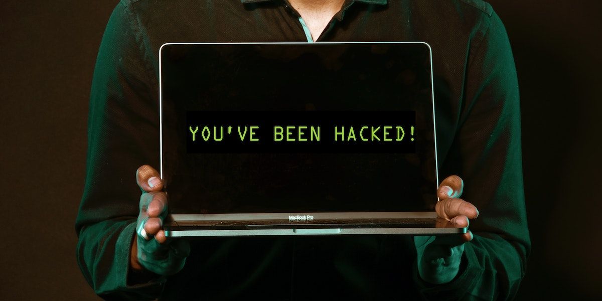 A person holding a laptop with both hands that reads youve been hacked