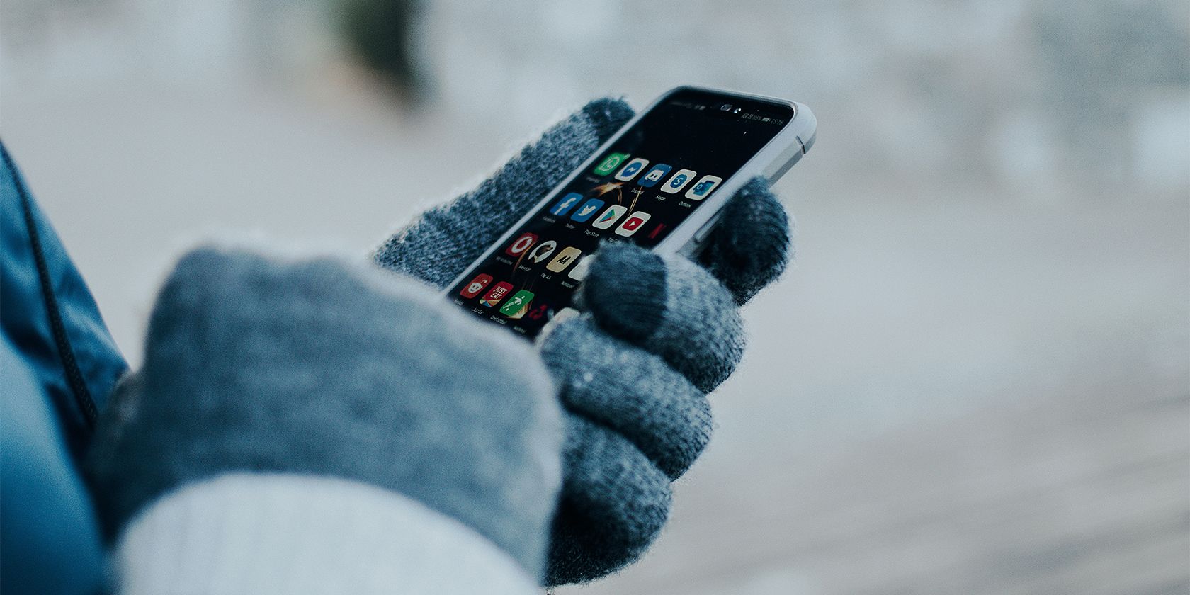 person wearing gloves while using a touchscreen smartphone