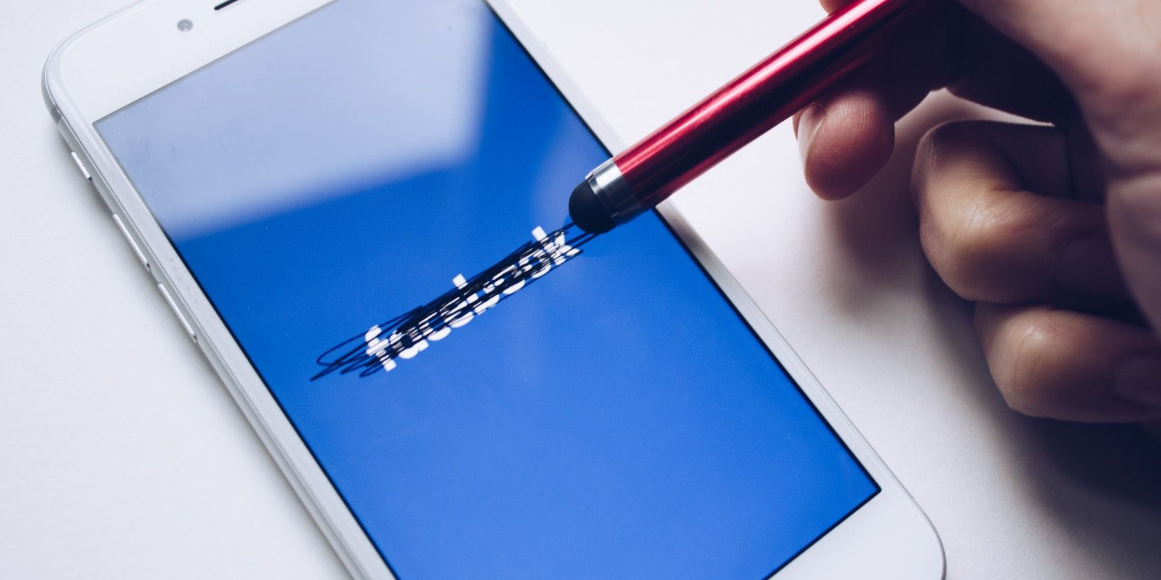 stylus scribbling over Facebook logo on iPhone