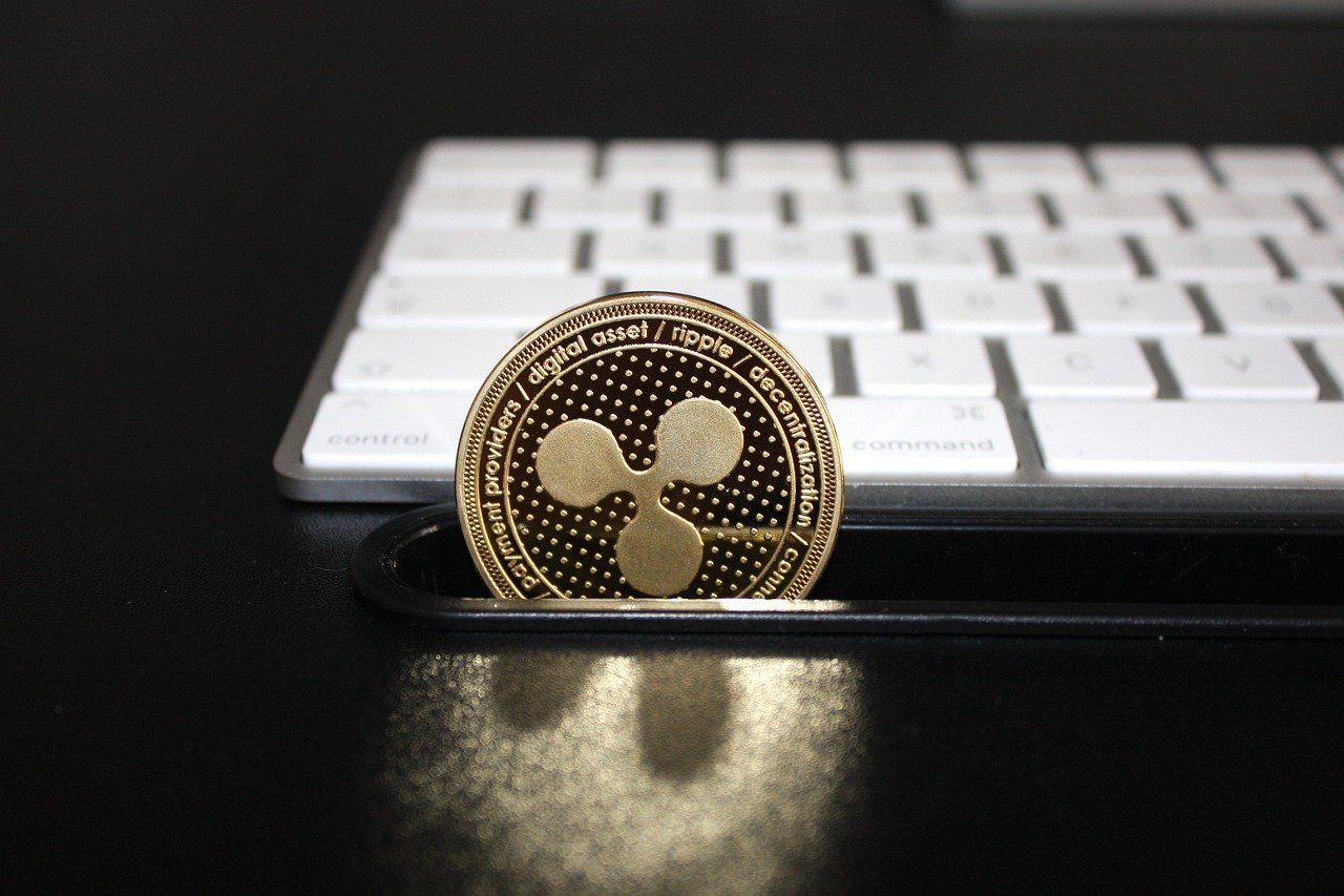 One Ripple coin placed on a black surface in front of a keyboard