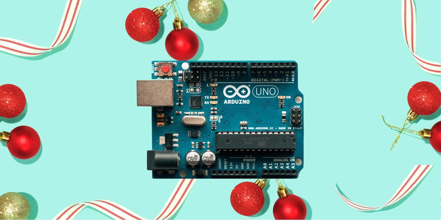 An arduino microcontroller board on a blue background with christmas decorations around the border