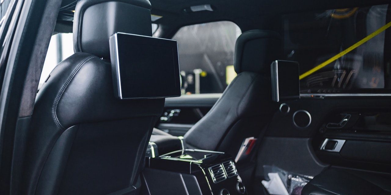 The inside of a car showing two screens mounted on the back of the front seat head rests