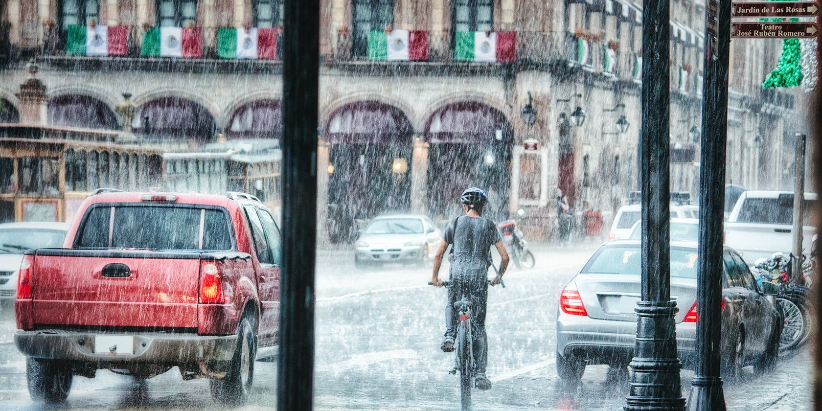 Person riding bicycle in the rain in traffic.