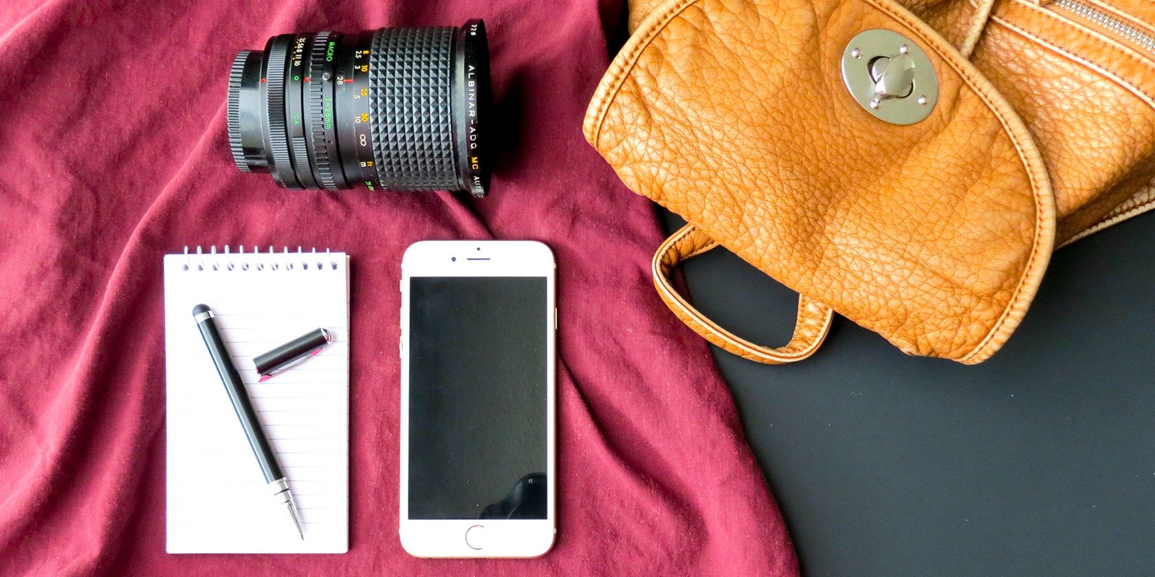 Camera bag, lens, and notepad with phone