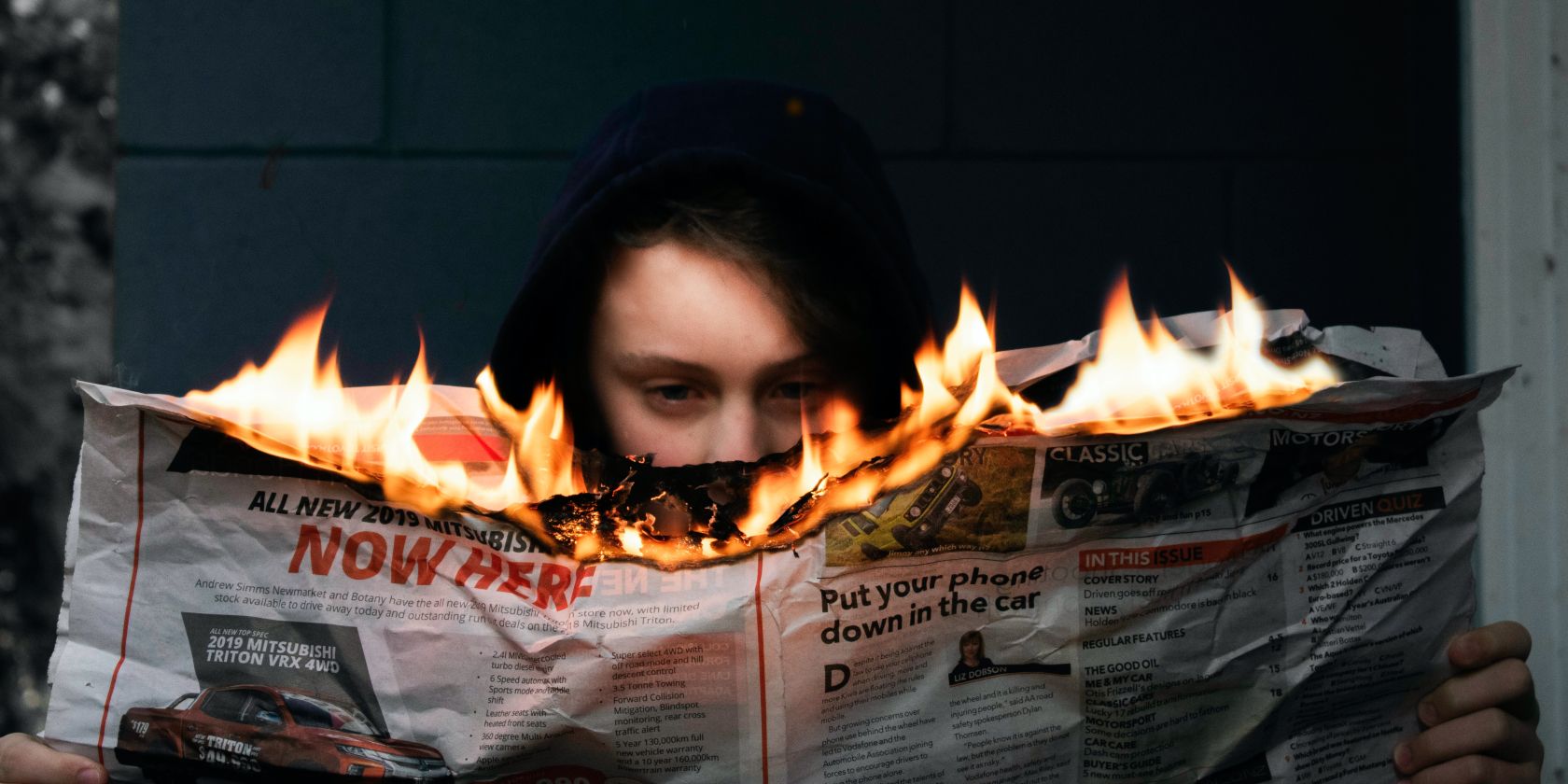 a person reading a newspaper on fire
