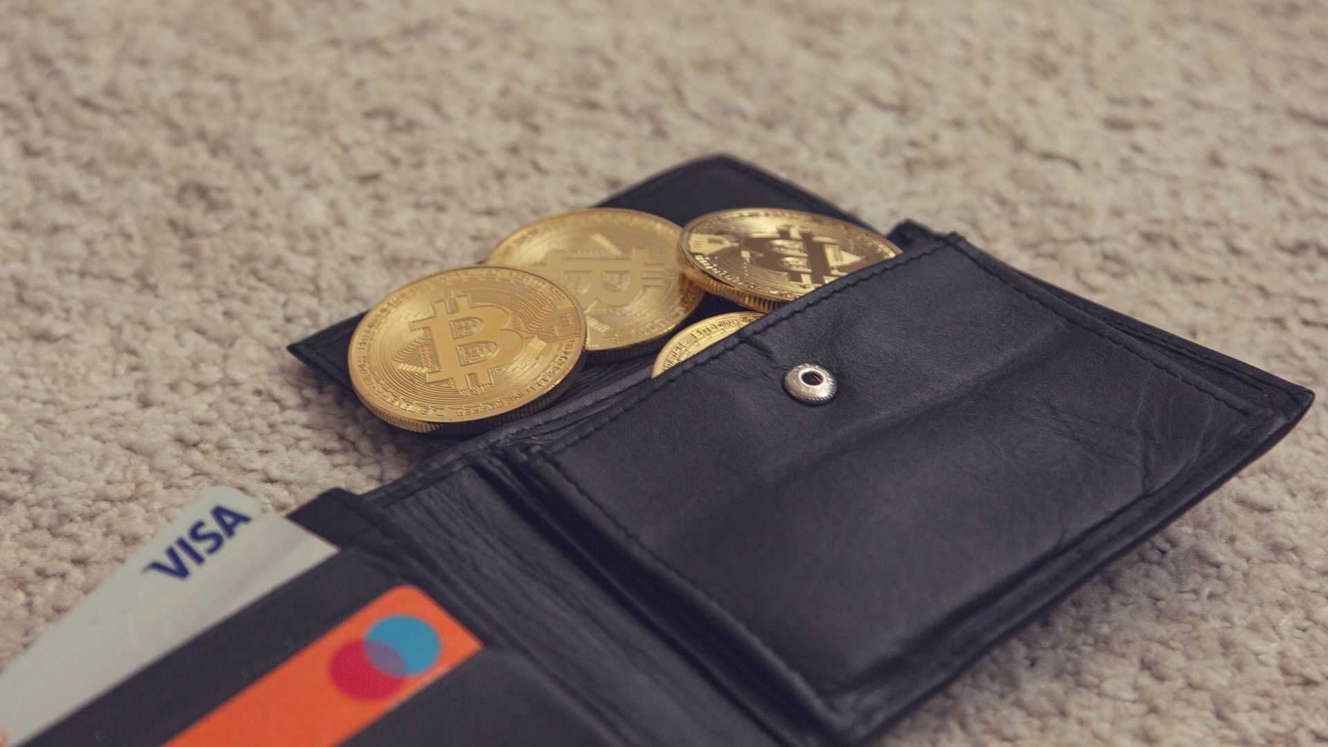 an open wallet with commemorative bitcoin coins spilling out