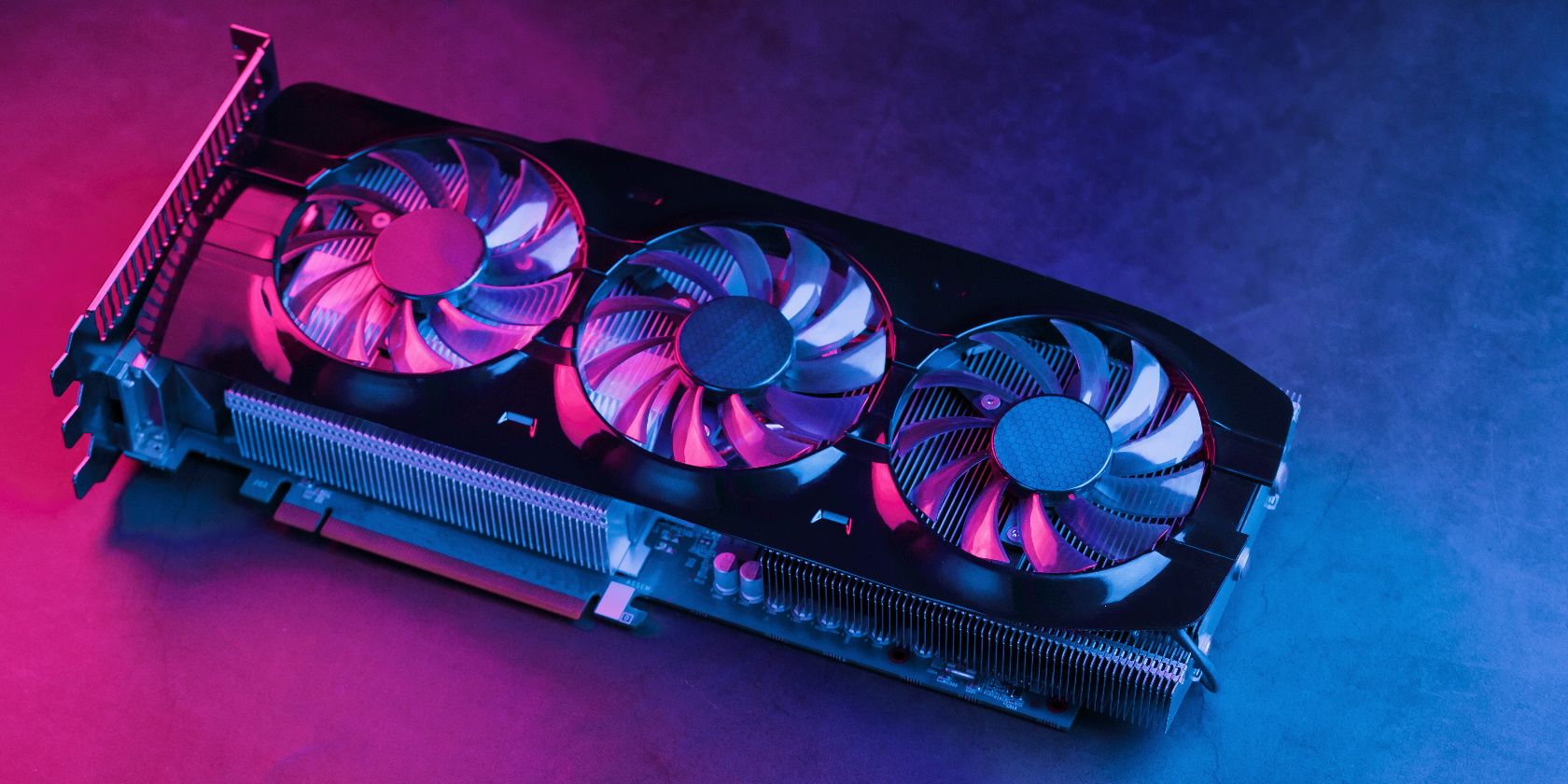 Large and powerful graphics card with three fans with blue pink light. The concept of a cyberpunk video chip for gaming and cryptocurrency mining. Dark key, top view