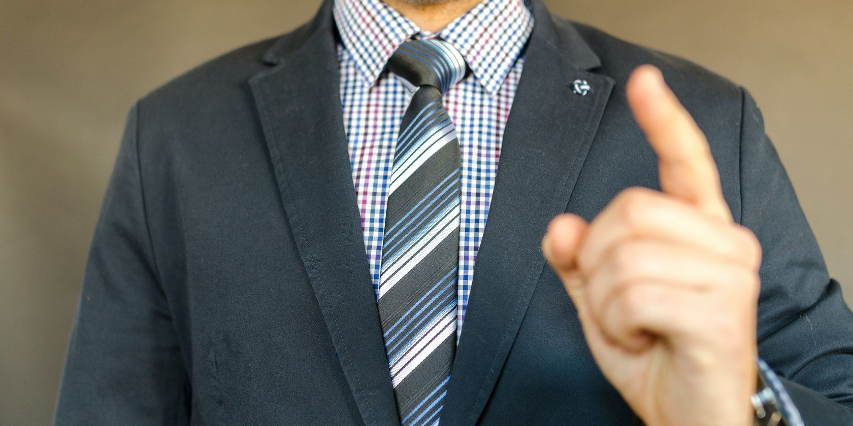 A man in suit pointing his finger at the camera